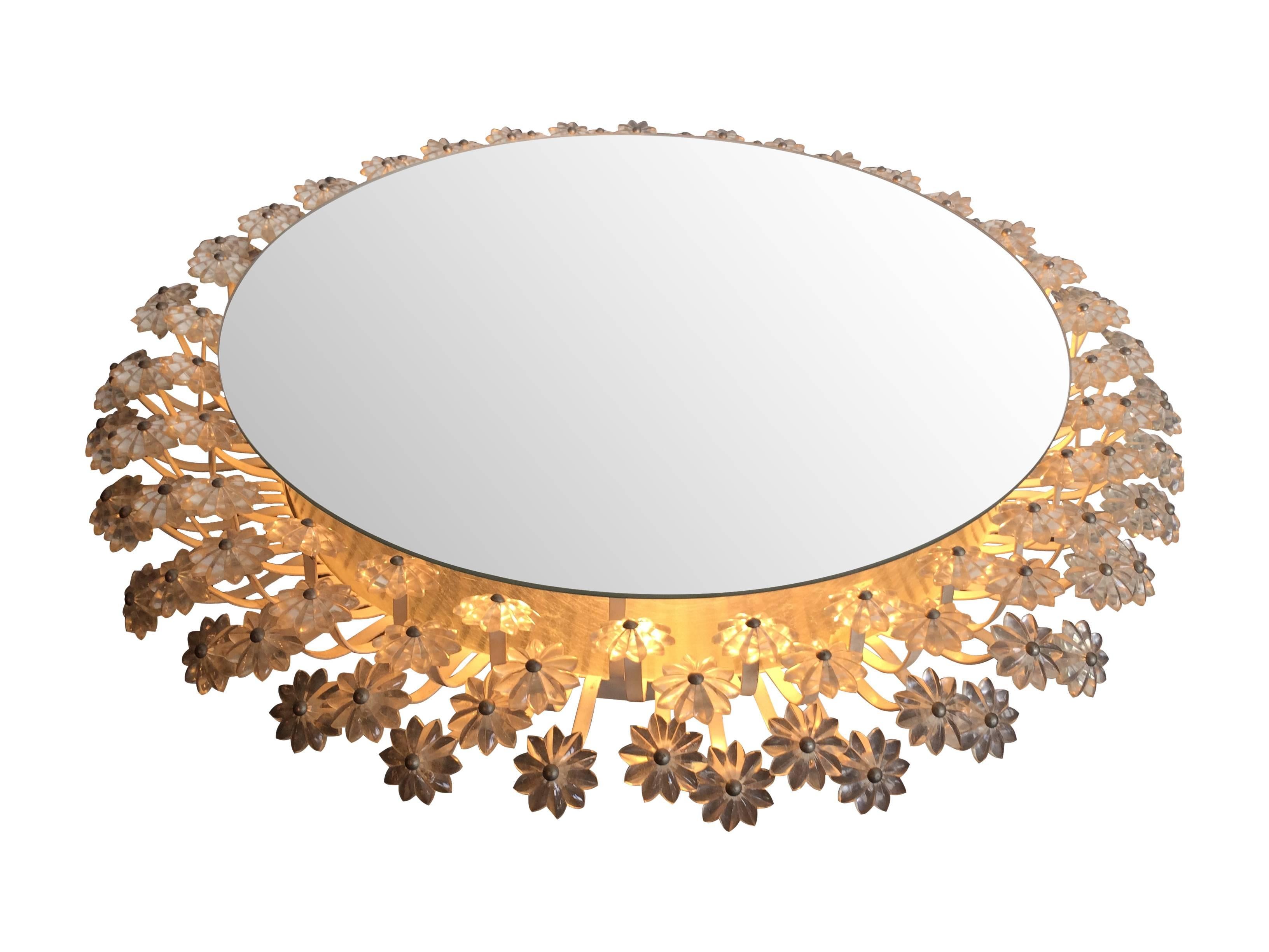 An Emil Stejnar circular backlit mirror, with a surround of over 120 small, clear acrylic flowers on a white enamel frame, with three lights mounted behind the mirror, re-wired and PAT tested.