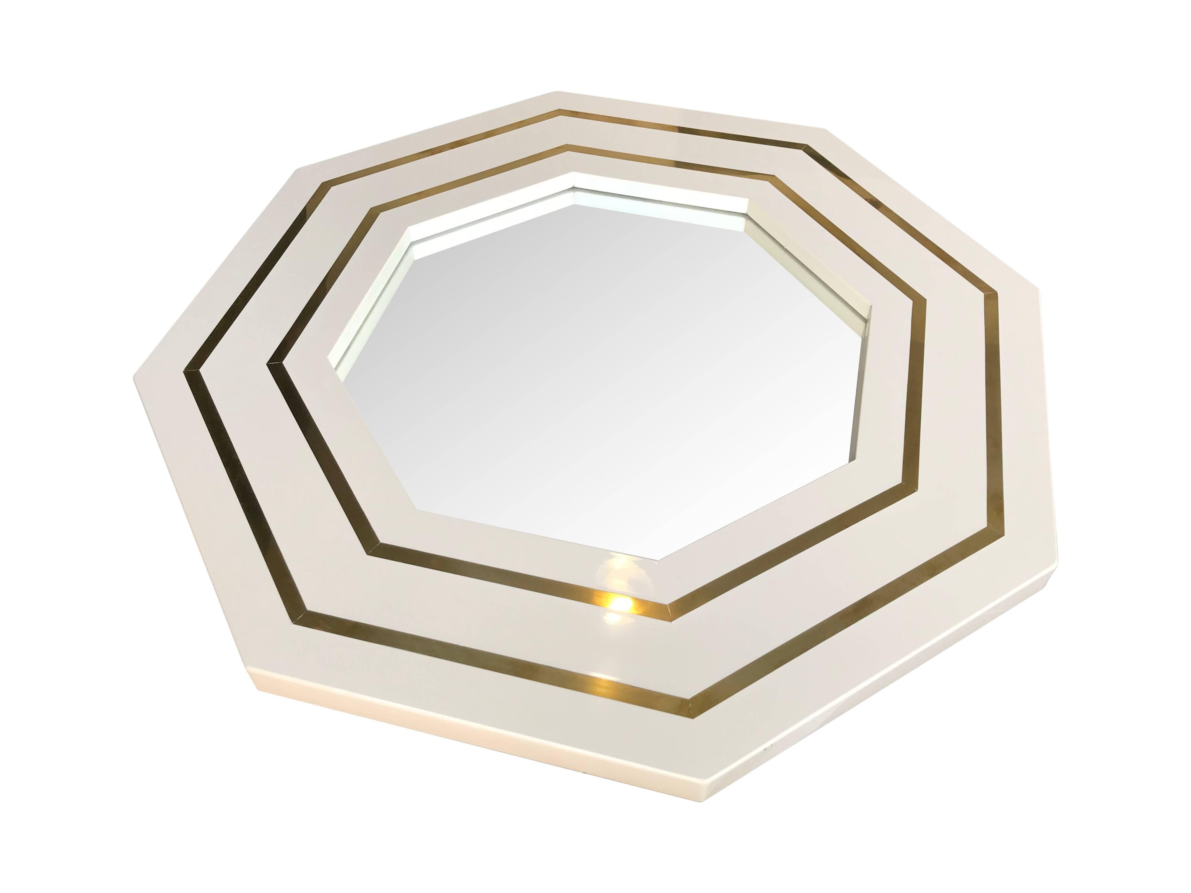 A Jean Claude Mahey octagonal mirror with ivory lacquer and brass inlay surround.
