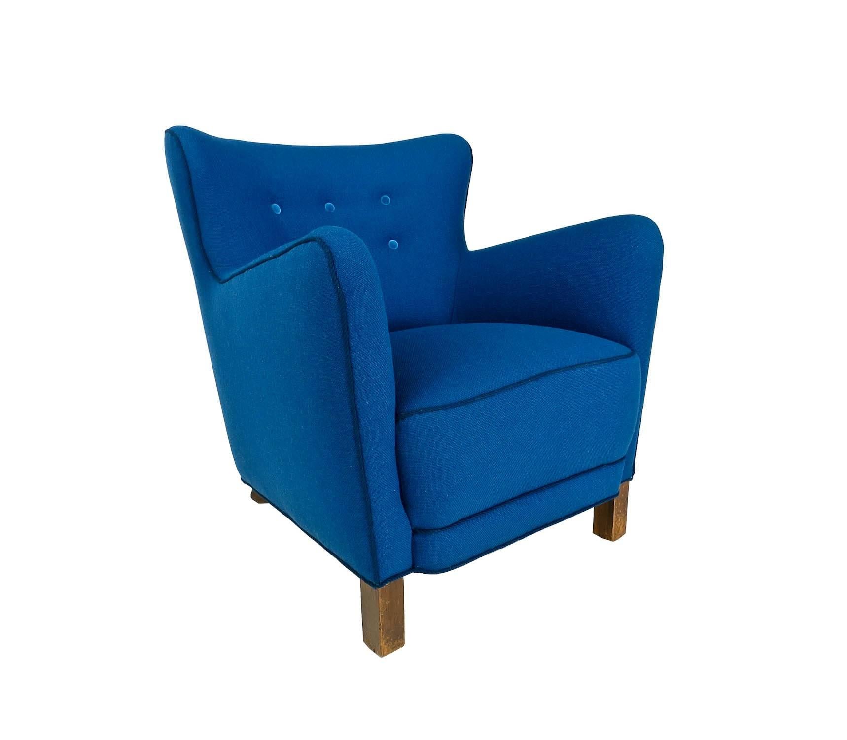 A beautiful Fritz Hansen armchair from the 1940s reupholstered in a blue wool fabric with velvet buttons and rope twist trimming. A curved shaped seat back flanked by high sided armrests, resting on square beech legs, all in an excellent original
