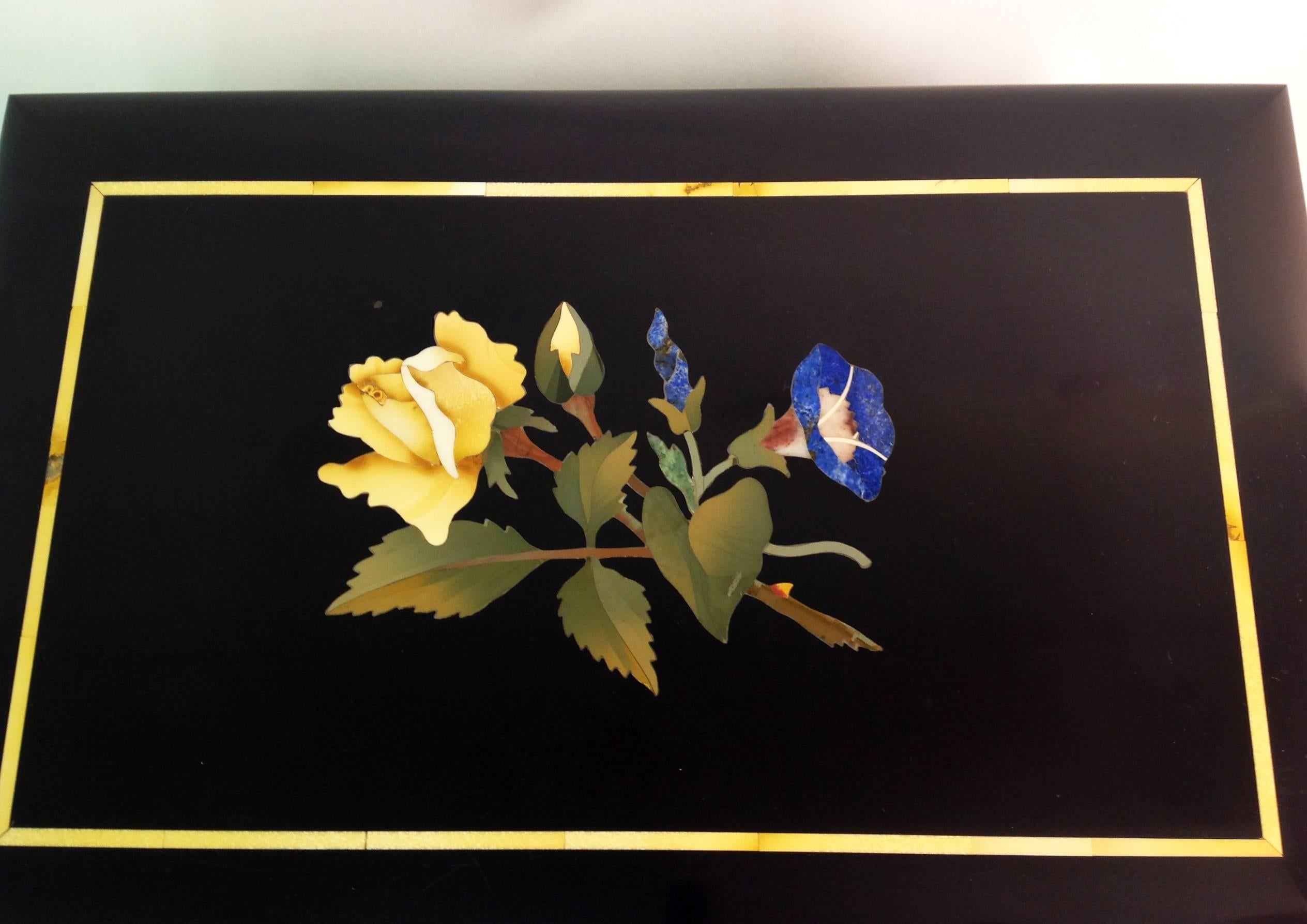 An elegant Belgian black marble hinged box with semiprecious stone decoration of yellow and blue flowers. Cut stone with a 1/8 inch bevel about the top, connected with a brass hinge. Italian private collection. Florentine handicraft. 
Weight kg