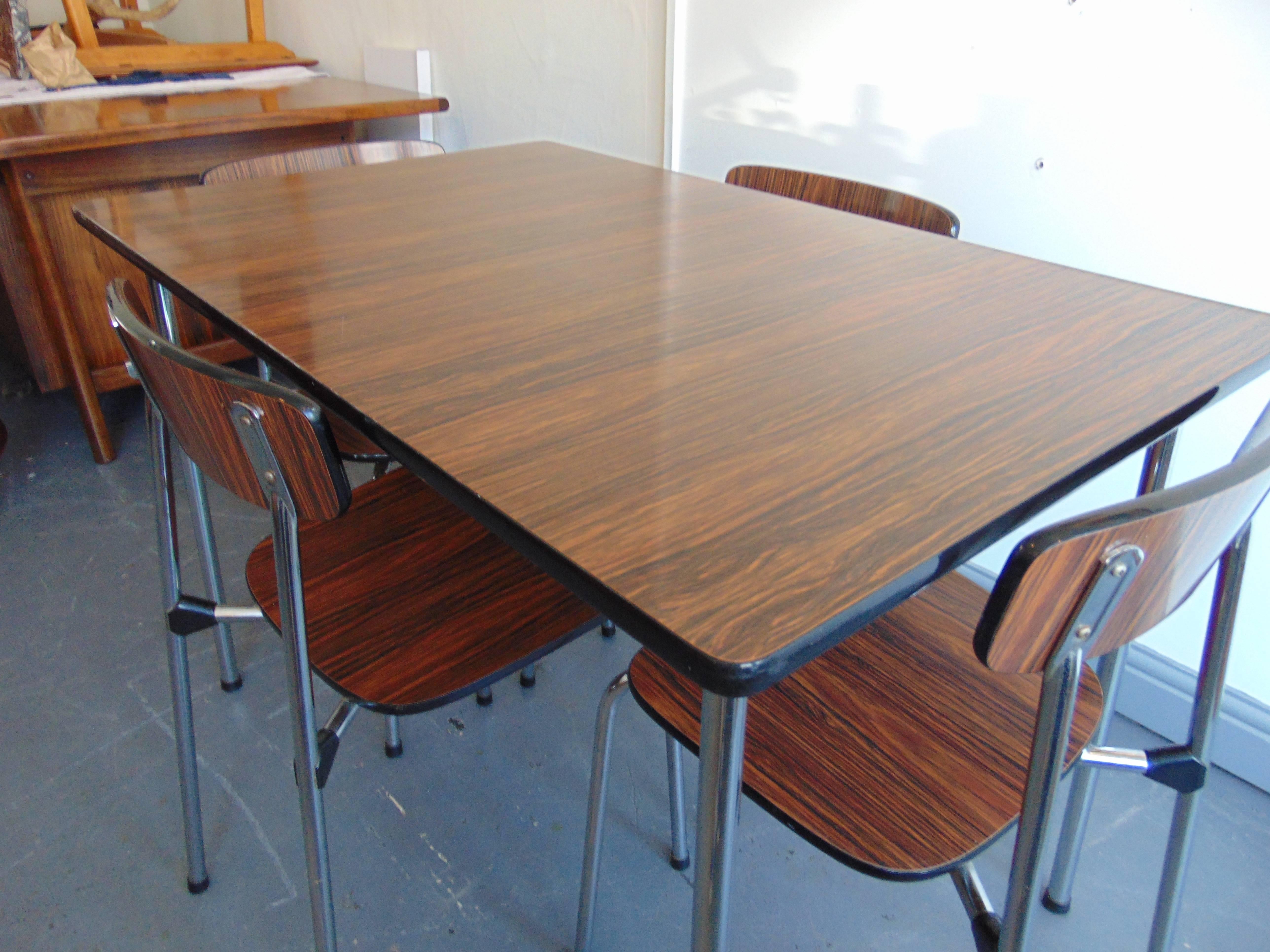Vintage dining table and four chairs by Tavo of Belgium.

A Mid-Century dining table and chair set from Belgium.
A simulated rosewood dining table on aluminum legs, together with four matching stacking chairs.
Manufactured by Tavo of Belgium in