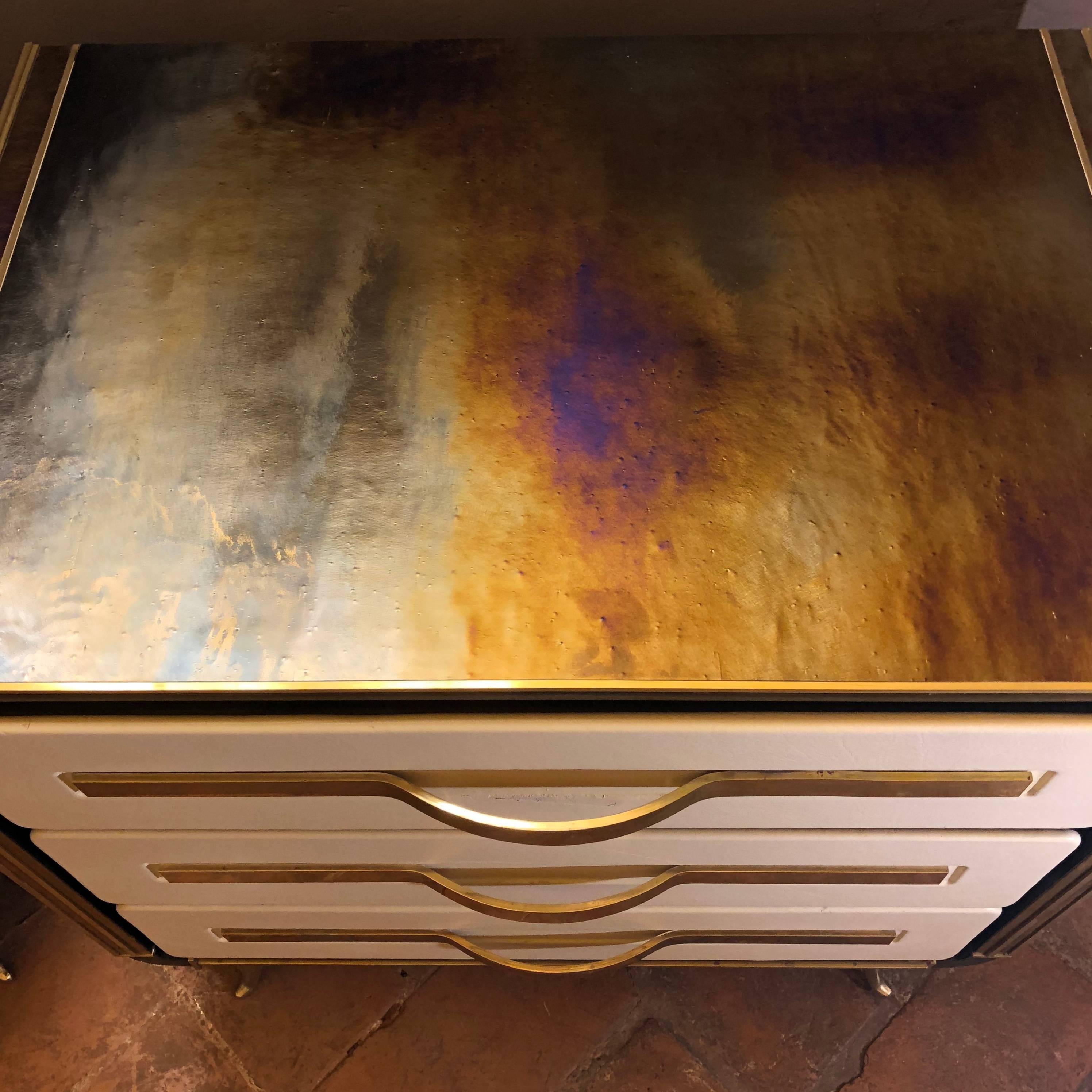 Wood chassis with brass detailing. Three drawers covered with off-white leather and solid brass handles. The gold green Murano blown glass is color changing.