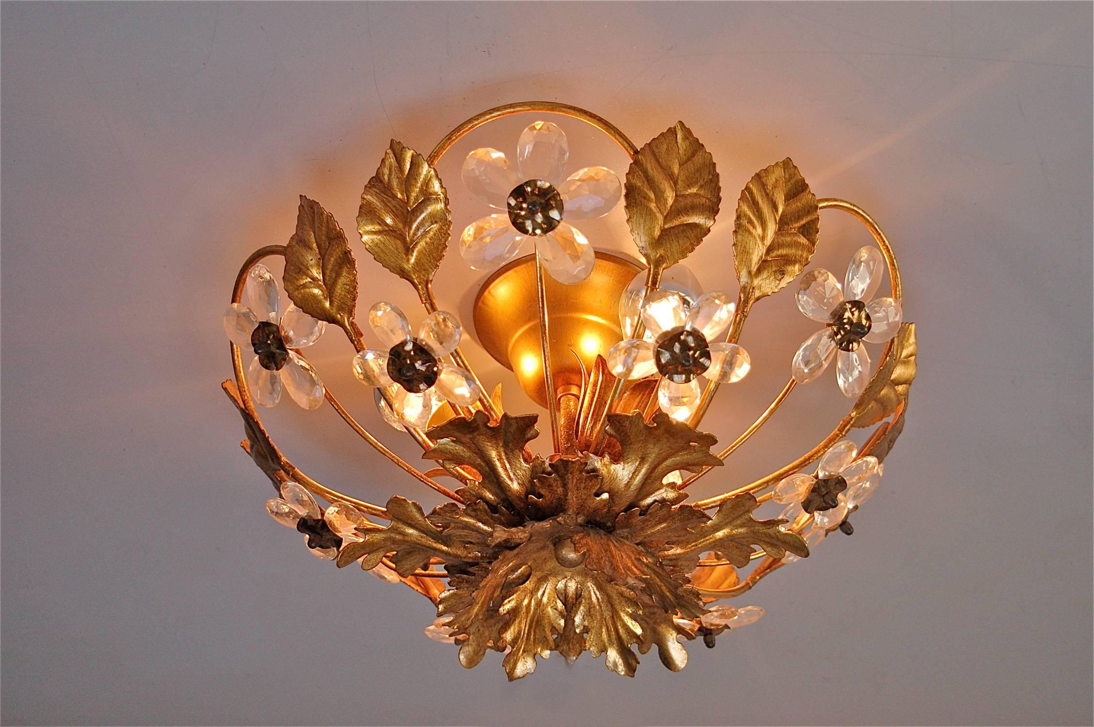 This gold coloured metal floral ceiling light, shaped like a basket, is decorated with hand cut crystal flowers that glisten in the light. Despite it being of the late 20th century, some patina has built up which enhances the warm glow. The light is