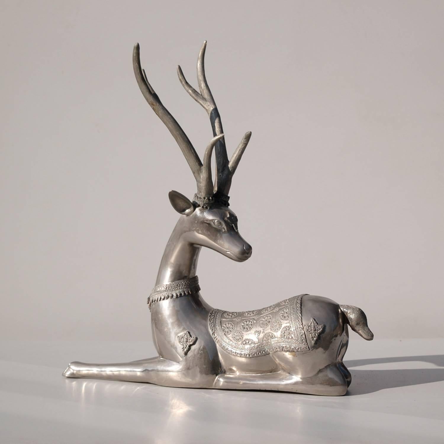 Decorative silver coloured statue or animal floor schulpture with fine detailing of a resting male deer or buck with antlers.