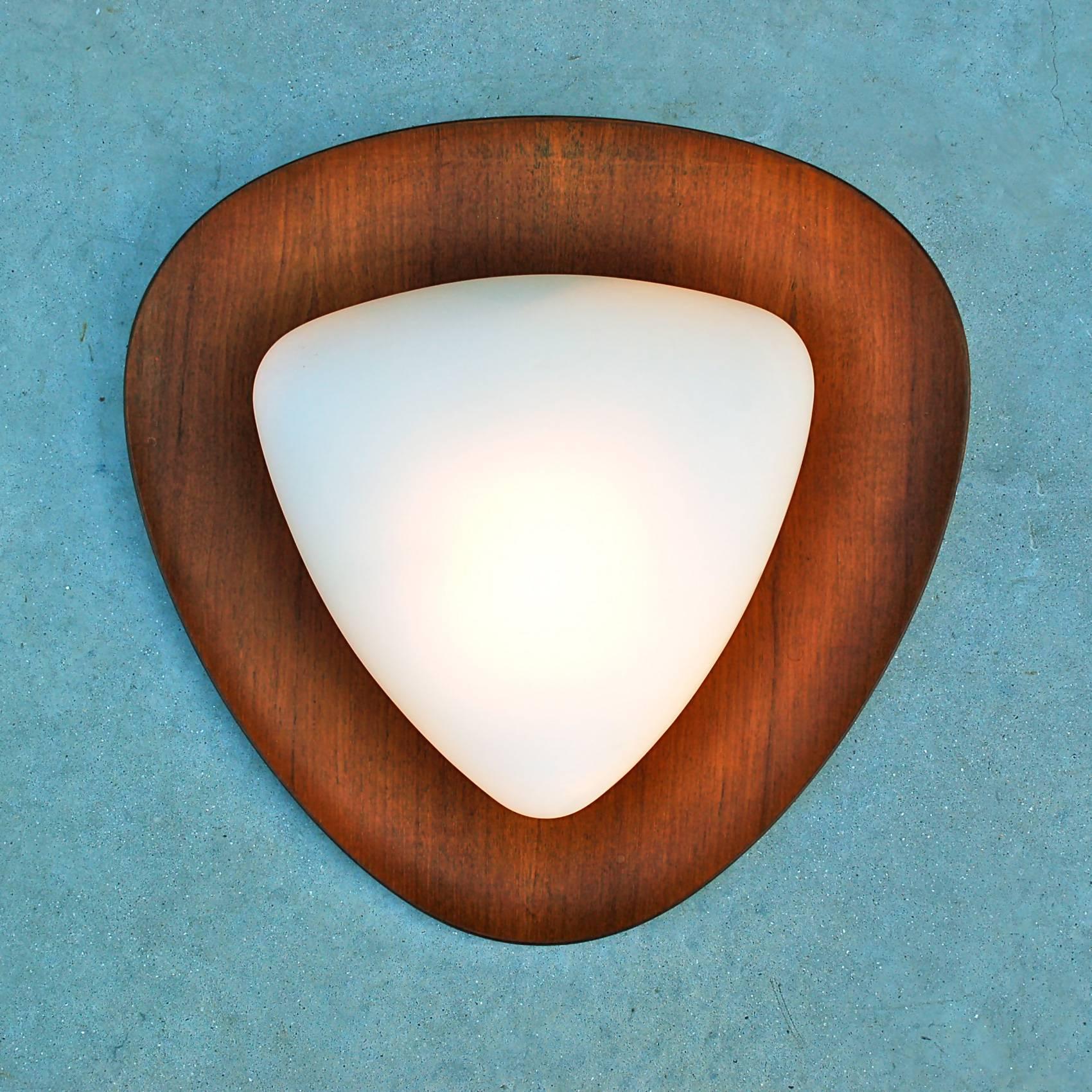 Triangular shaped wall light designed by Goffredo Reggiani on a teak wooden base with opaline shade which produces an atmospheric diffuse light. The sconce is fitted with a standard European screw bulb fitting and wiring. We can rewire/refit on