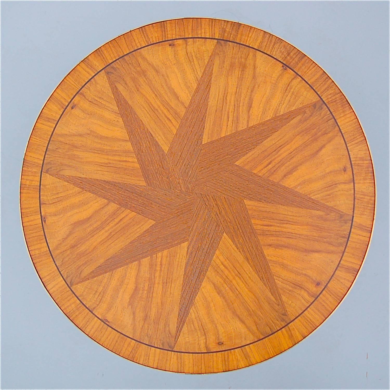 Elegant three-legged side table with decorative wood inlay in the shape of a star. The use of different shades of color and wood grain give the tabletop a very dynamic appearance. The edge has a brass trim, adding a wonderful highlight and touch of