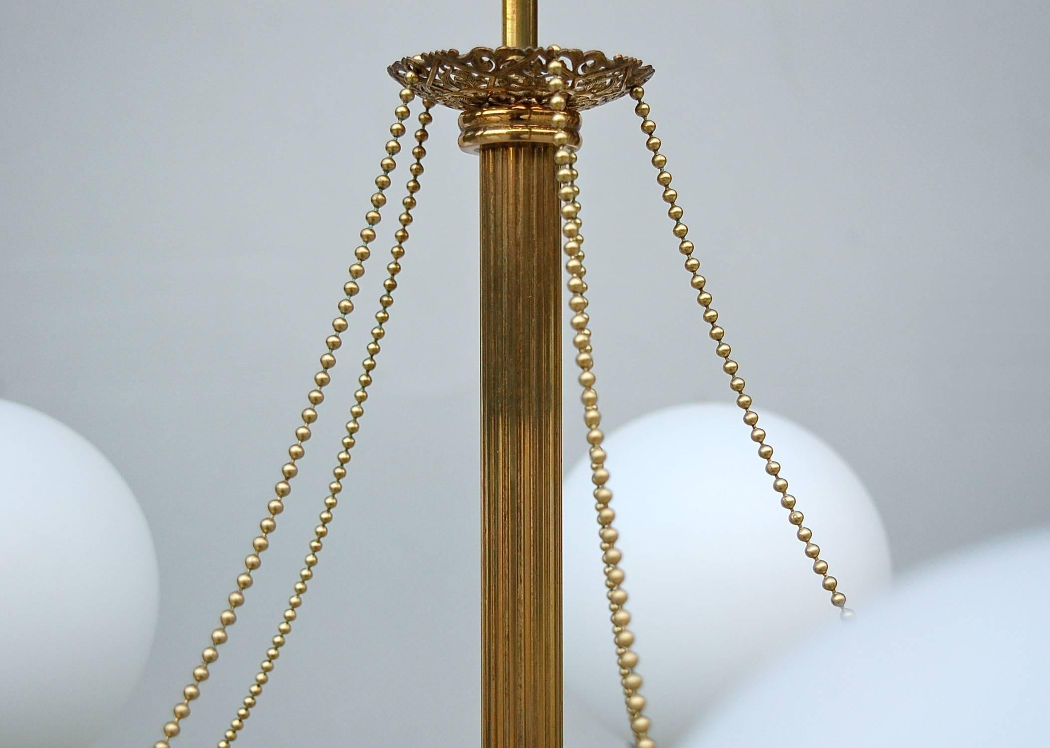 This ceiling lamp is very evocative of the early 20th century. A survivor of its time, it probably hung in a French bistro, hotel or cafe. The central fluted stem and curved arms are made from brass and are linked by delicate pearl shaped chains.