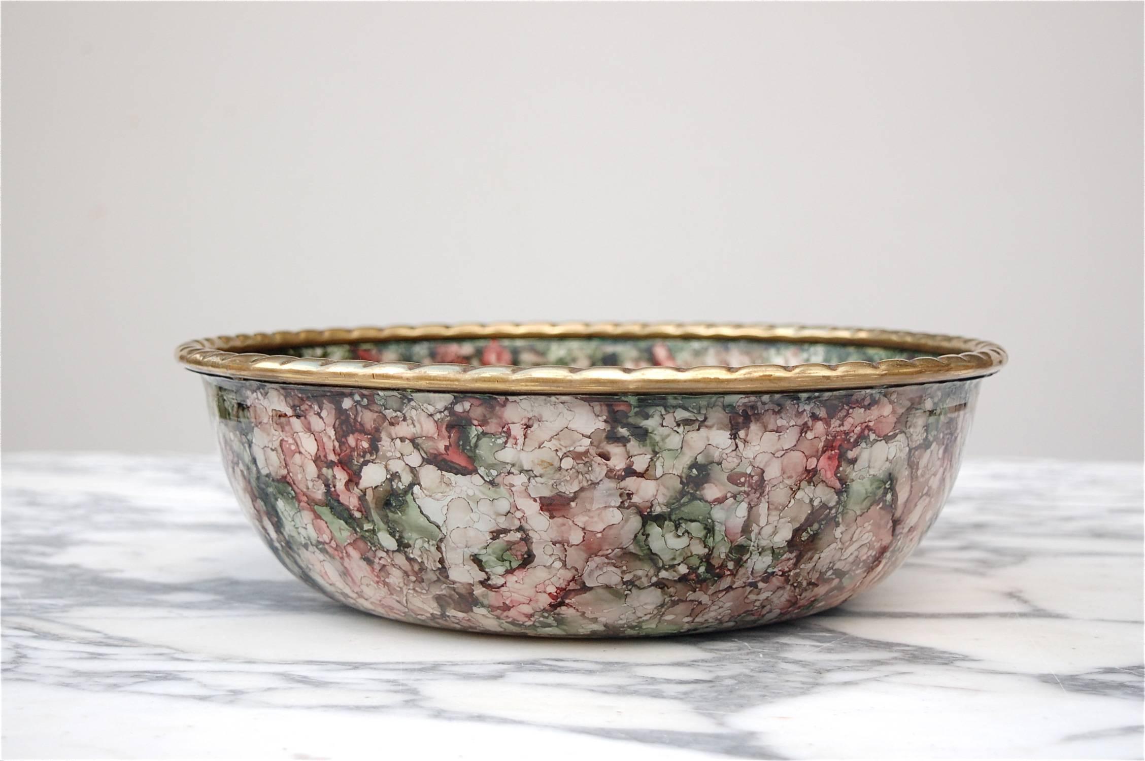 A solid brass bowl or dish with enamel decoration and twisted rope style rim. Unlike cloisonné, the bowl is decorated in a very fluid, freehand style of enameling resembling a smooth blend of multicolored watercolor splashes or even mosaic inlay