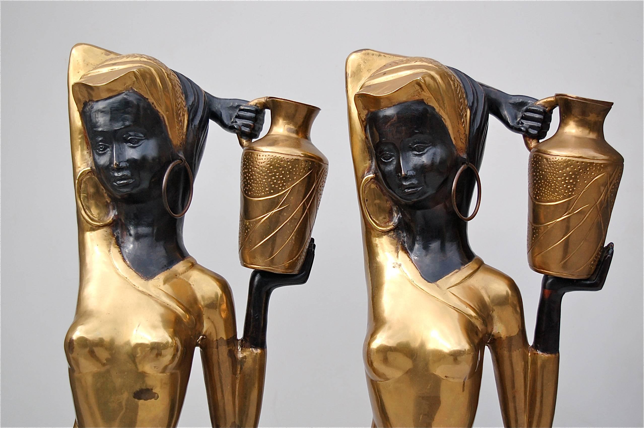 Highly decorative, two-tone floor sculptures of two African females in striking pose. The garments have a gold colored finish and are draped in such a way to accentuate each shapely curve of their bodies. It's a more contemporary interpretation of a