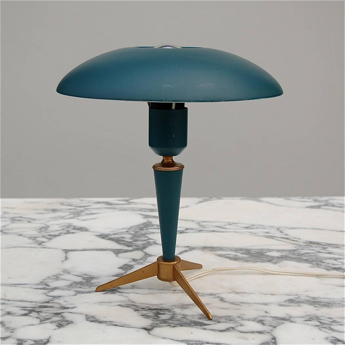 The design of this table lamp by Louis Kalff has something outer-worldly about it, not surprisingly as it dates back to the late 1950s, the age synonymous with space exploration. The lamp rests on a brass tripod and still has its original blue