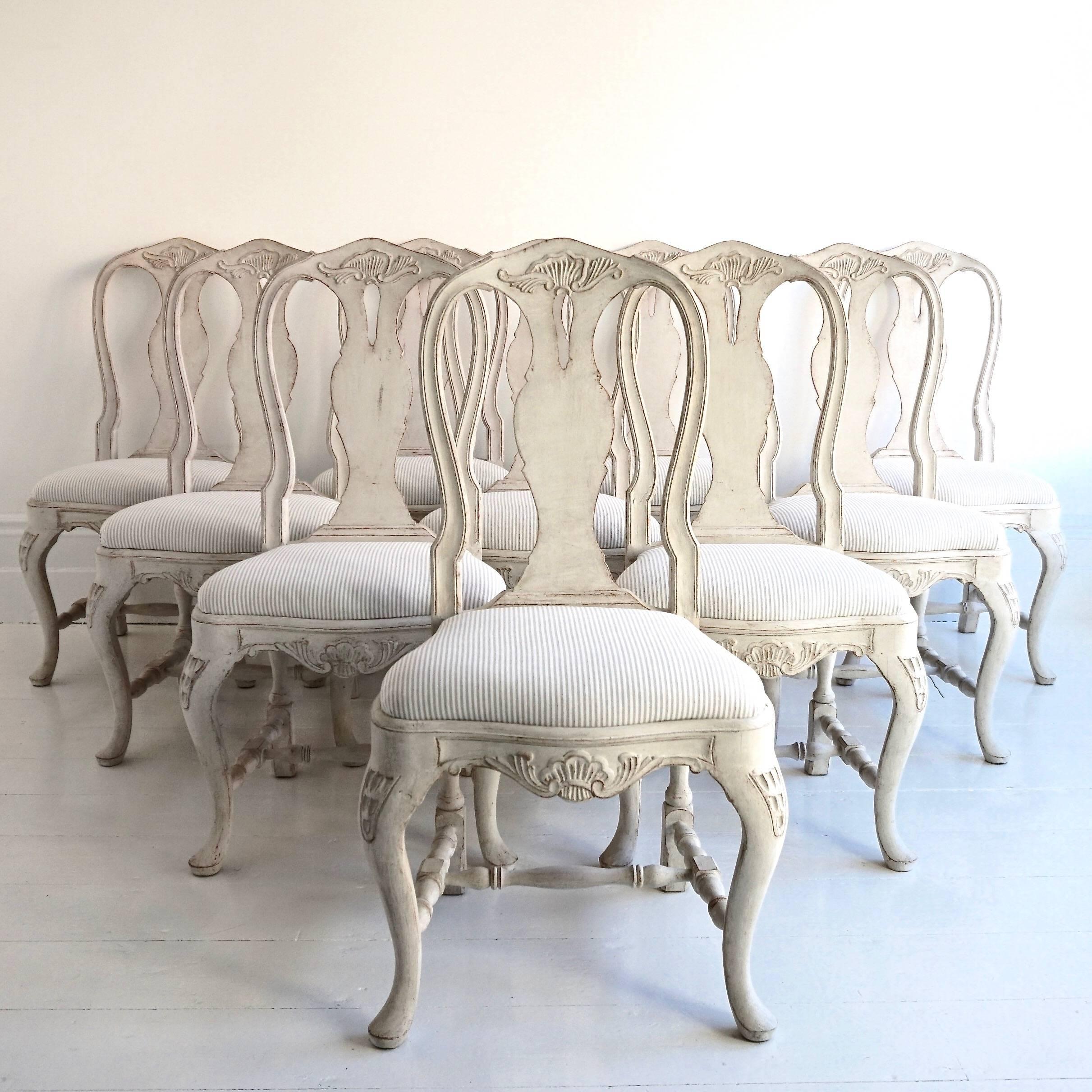 A magnificent set of ten very fine and richly carved Rococo style dining chairs, recently upholstered in a beautiful Romo ticking stripe, Swedish, circa 1910.
   