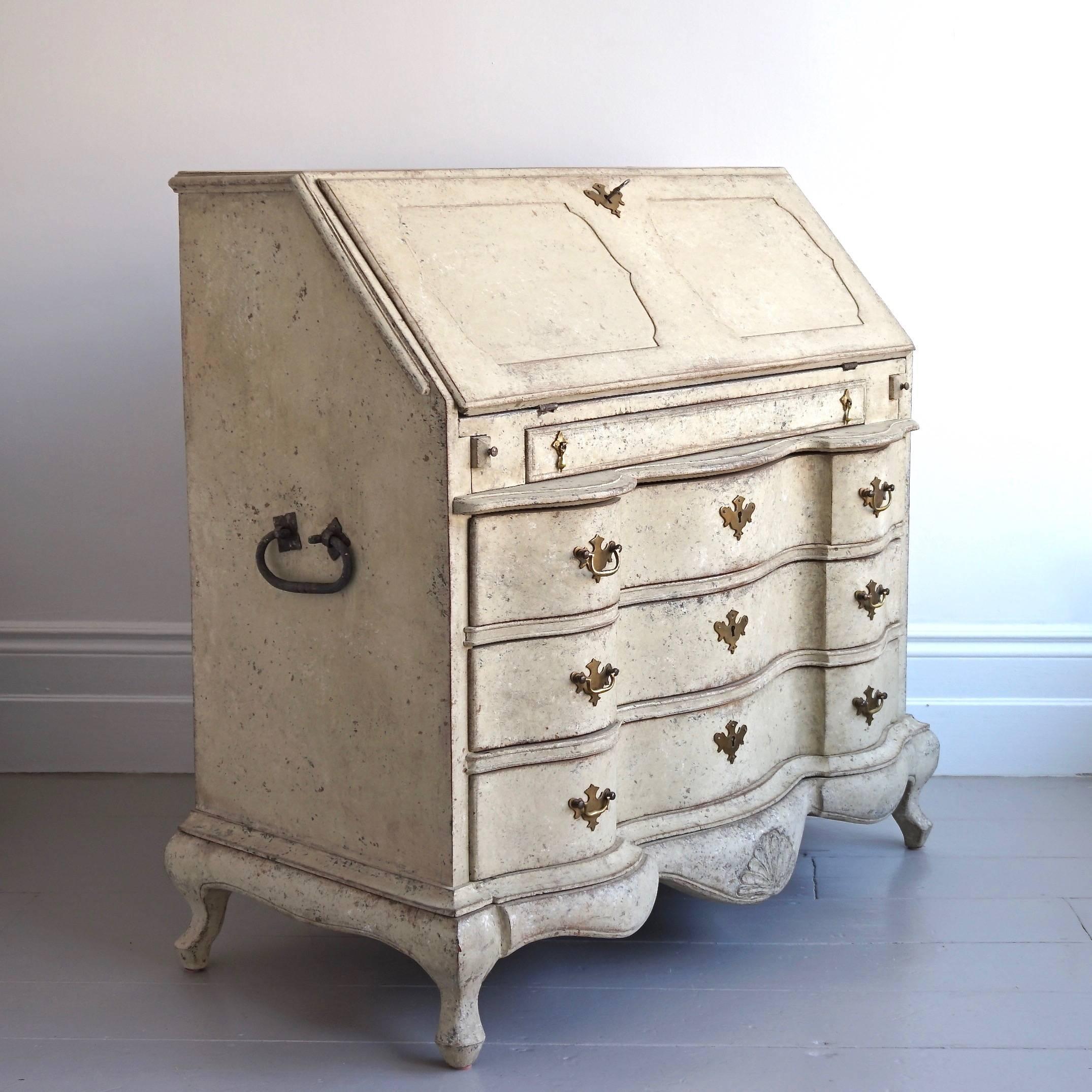 A stunning Baroque bureau with an outstanding antique patina. The bureau features a decorative inset panelled desk lid concealing a beautiful interior with curved drawers and secret compartments, a slim letter drawer over three hand carved