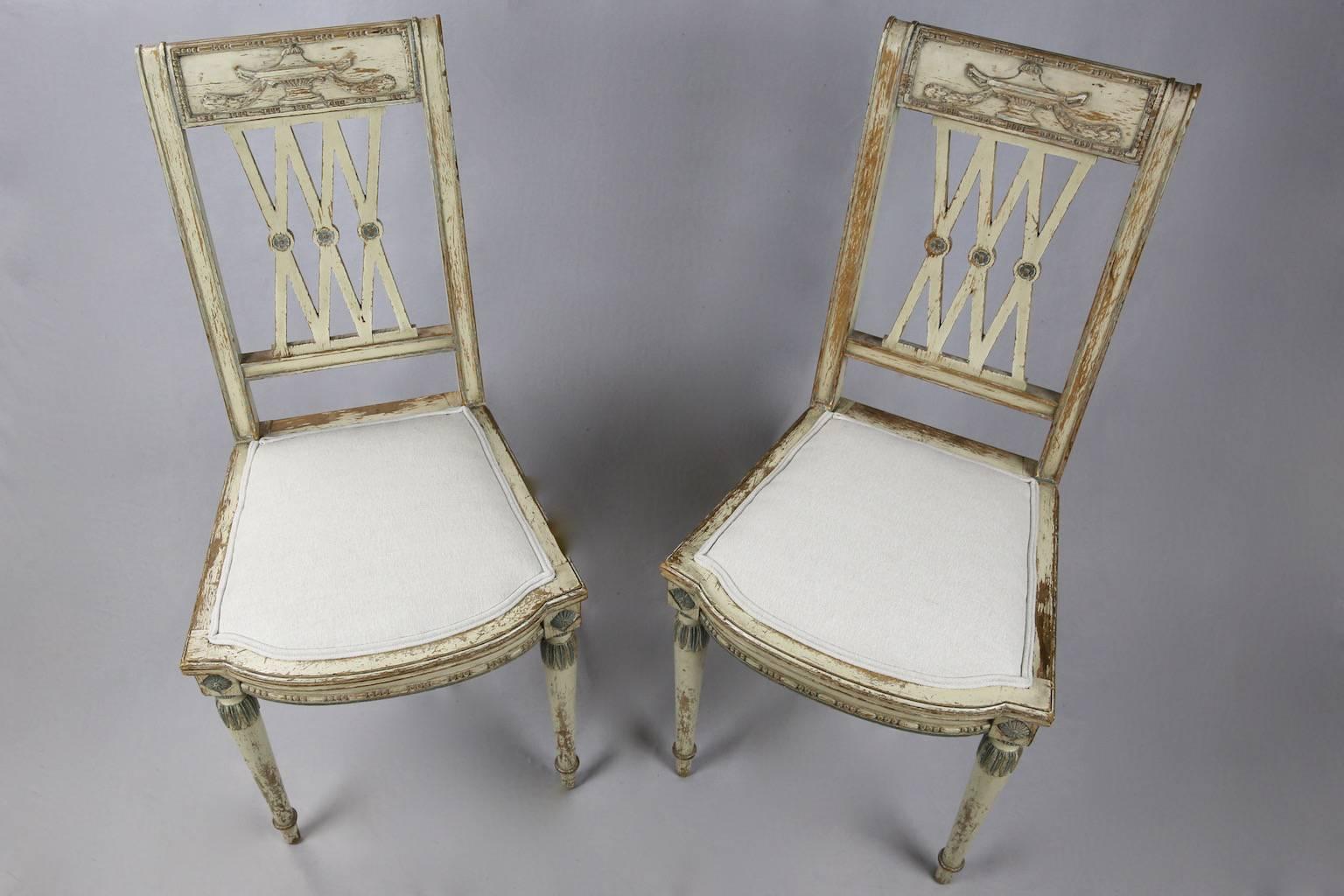 Empirical Evidence: Absolutely charming pair of French chairs in their original off-white and blue paintwork. Recently re-upholstered in a linen mix, each seat features an elegant lattice back embellished with roundels, back rail surmounted with a