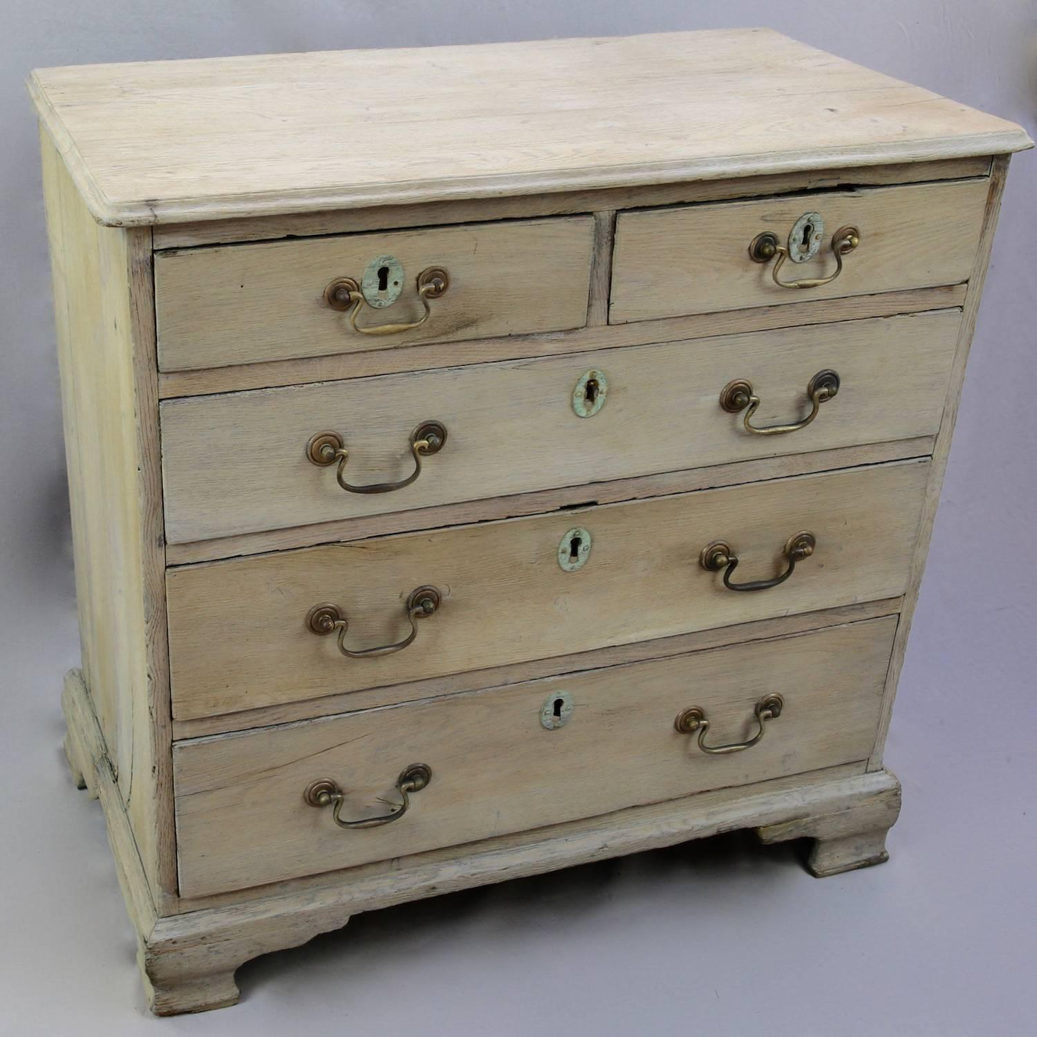 By George! An early oak English chest of drawers dating to circa 1770. Provincially constructed, this piece has a rectangular moulded top and two short drawers over three, graduated full-length. With brass swan neck drop handles and ogee shaped