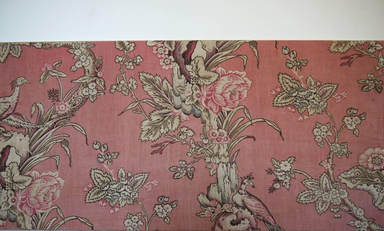 A French, late 19th century linen textile printed with exotic birds and a meandering branch or trunk of roses and leaves. Faded to a very pretty soft dusty pink with pale blue touches. Mounted on a pine stretcher.