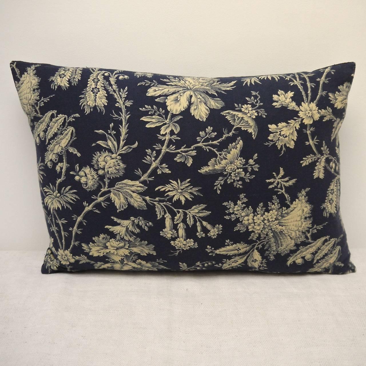 French printed cotton cushion, circa 1870s. A design of exotic flowers and meandering branches printed in cream on a inky blue textured cotton. Backed in a dyed blue/black linen and slipstitched closed with a duck feather pad insert.