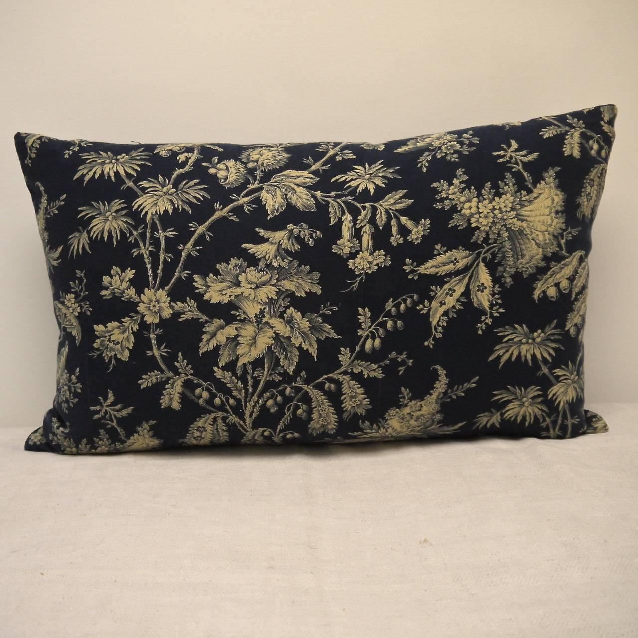 French printed cotton cushion. Printed with a design of exotic flowers and meandering branches on a textured cotton. Backed in a dyed blue/black linen and slipstitched closed with a duck feather insert, circa 1870s.