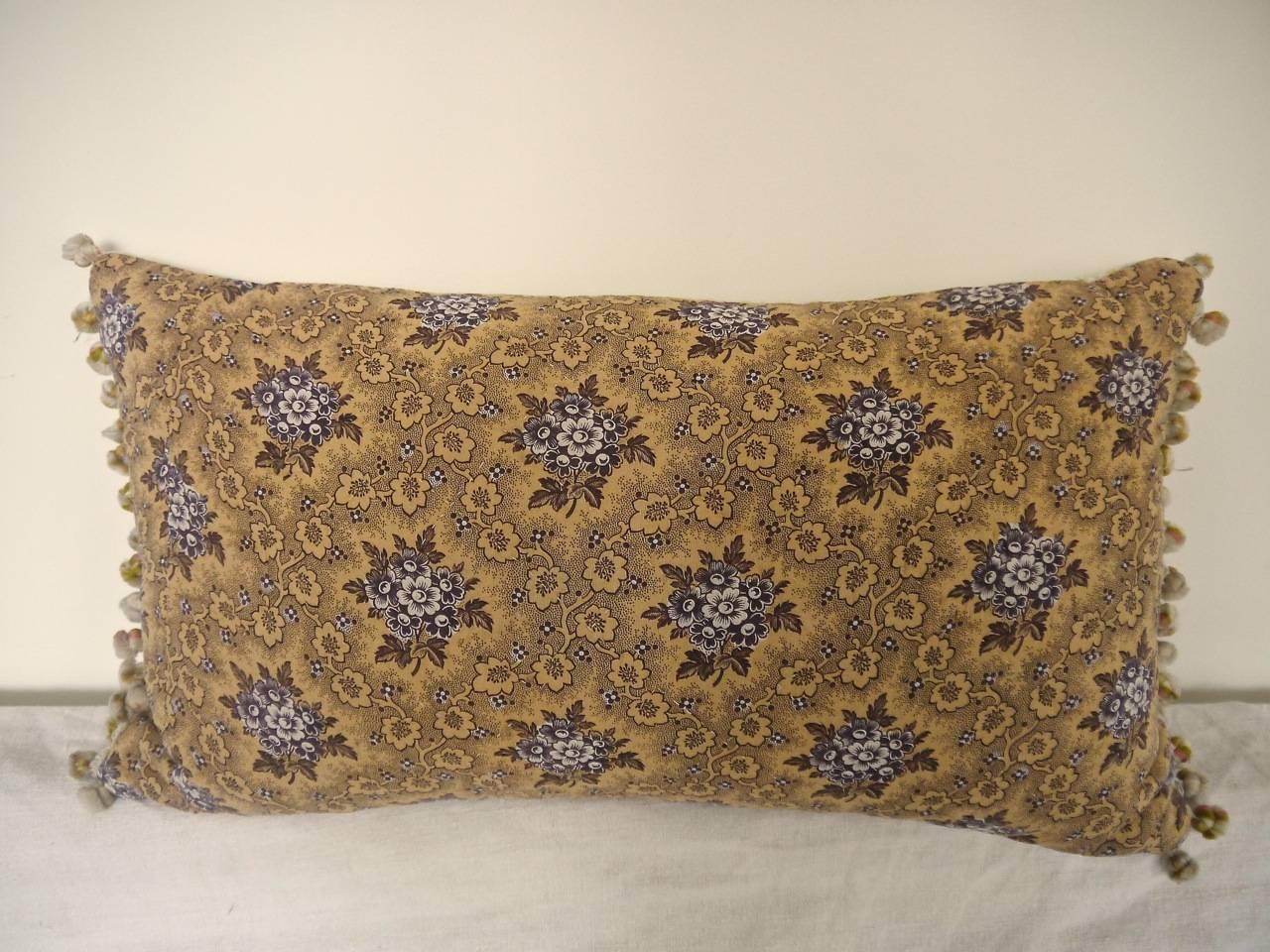 French mid-19th century printed cotton and quilted cushion edged in a pretty French antique wool bobble trim. Backed in the same quilted design with a pale yellow simple striped print. Slip stitched closed with a duck feather insert.