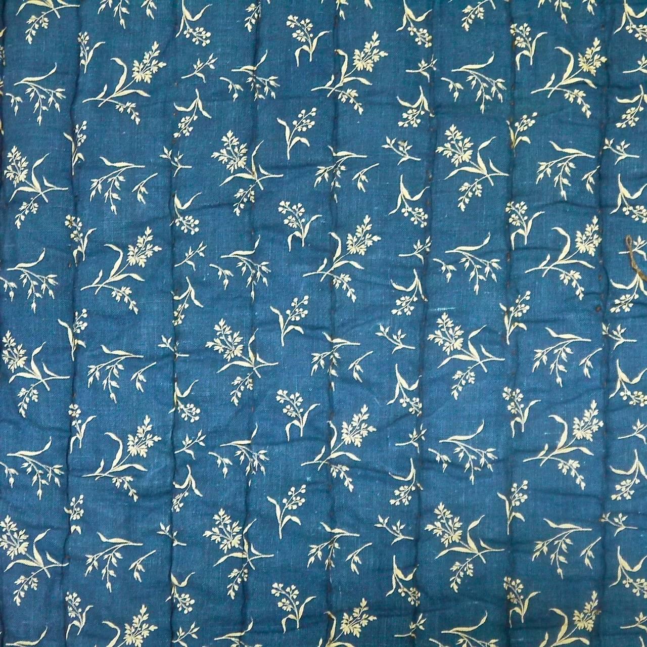 French mid-19th century indigo cotton quilt one side a simple small all-over floral, the other small is darker blue printed with small rice shapes.