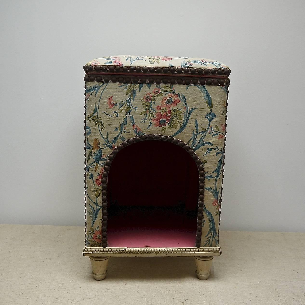 Charming and unusual French late 19th-early 20th century antique dogs bed upholstered in a pretty cotton textile with a pink cotton lining. Edged with iron studs on a ribbon trim.The top lifts up to reveal a small storage space. Beautiful and rare