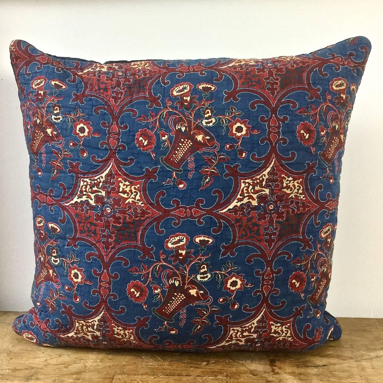 French early 19th century block-printed cotton and quilted cushion. Stylized baskets of flowers in an interesting color combination of petrol blue and a reddy brown. Backed in a natural indigo hand-dyed 19th century French linen. Slip-stitched