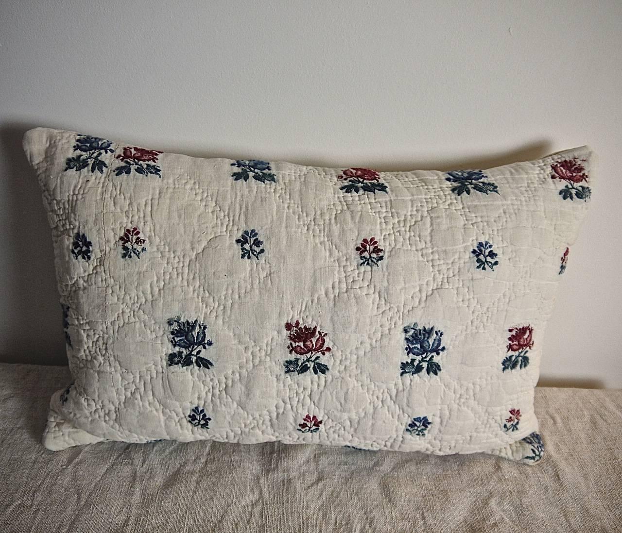 French late 18th century cambresene (wool woven on linen) quilted cushion with a design of alternate red and blue flowers with green leaves. Backed in a 19th century French linen. Slipstitched closed with a duck feather insert.