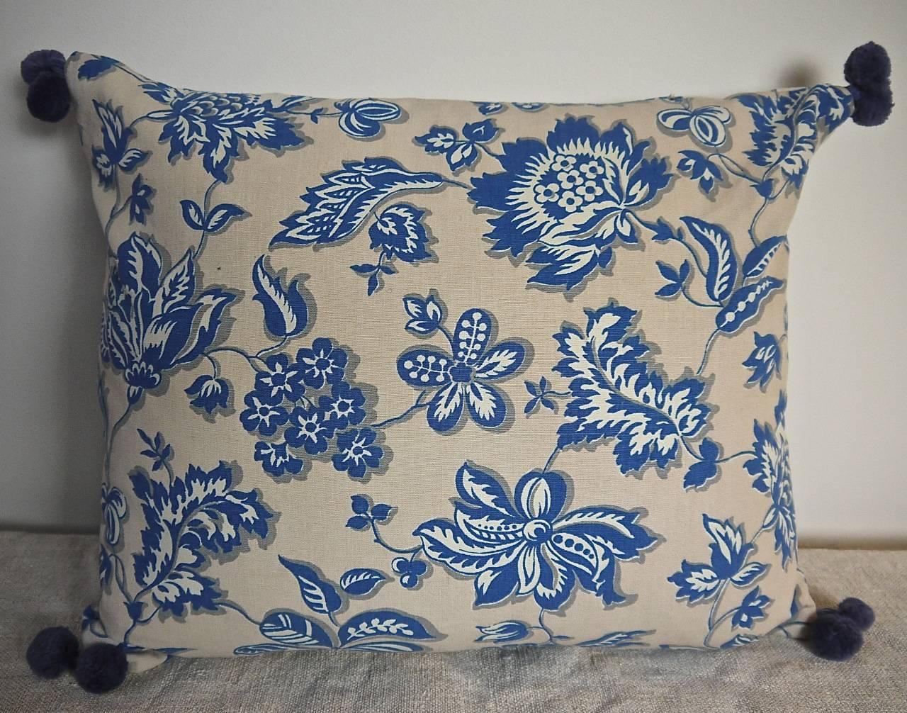 French cotton cushion printed with stylised fresh blue and white flowers and leaves on a soft off white ground, circa 1930-1940s. Backed in the same design with vintage French blue cotton bobbles on each corner.Slip-stitched closed with a duck