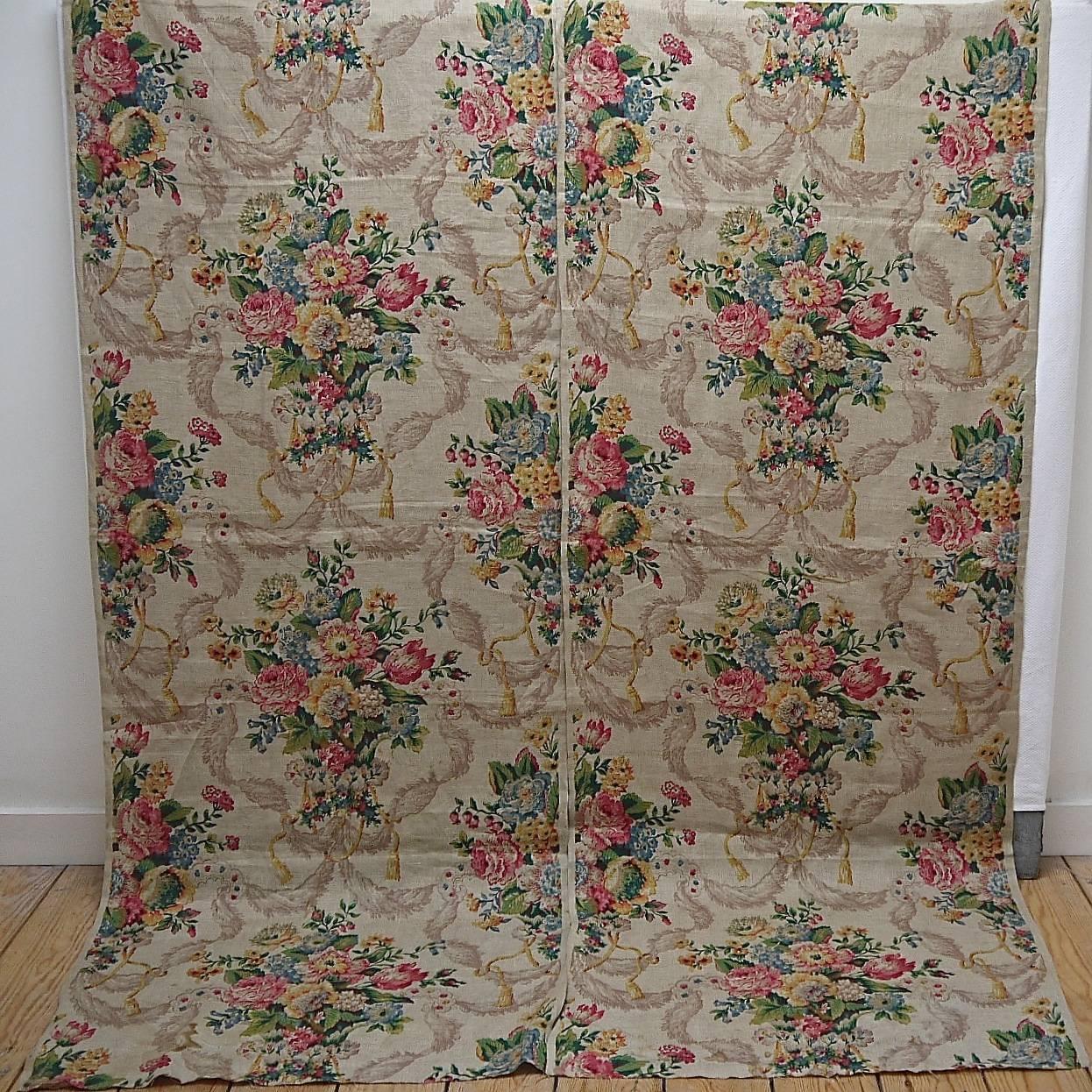 Pair of English, circa 1920s linen panels printed with a large display of mixed flowers in an urn, surrounded by swagged tassels. Lovely colors on a pale beige ground.