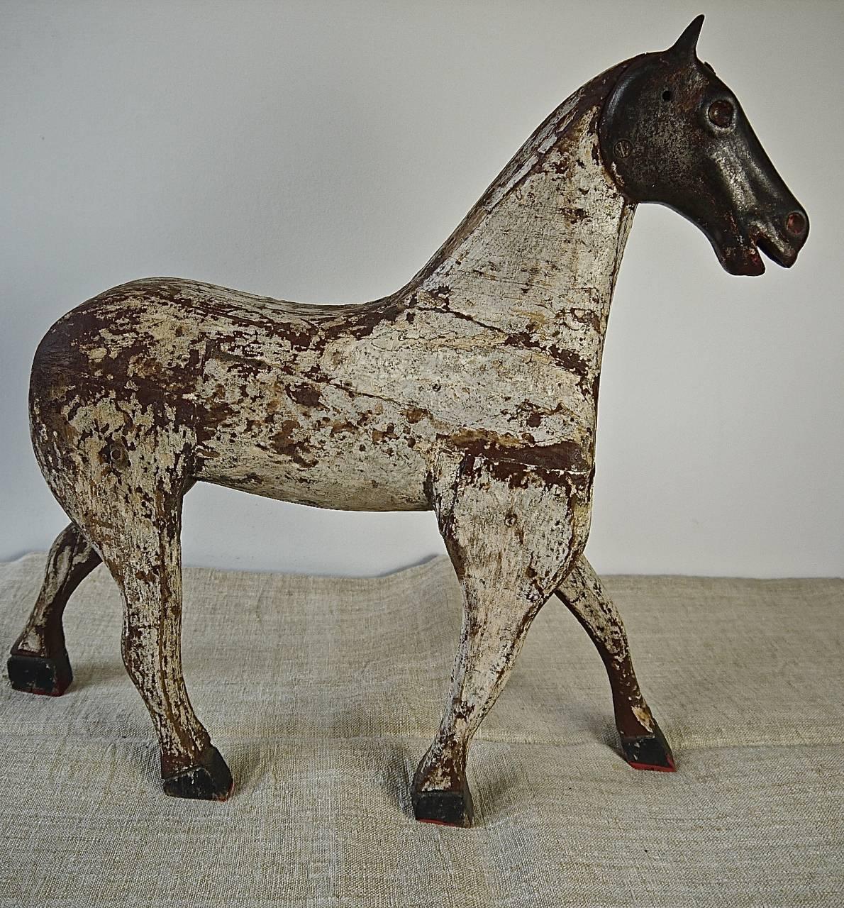 Unusual French late 19th century carved wooden and painted toy horse with an iron head and an elegant stance. Painted white with the remains of some later brown paint.