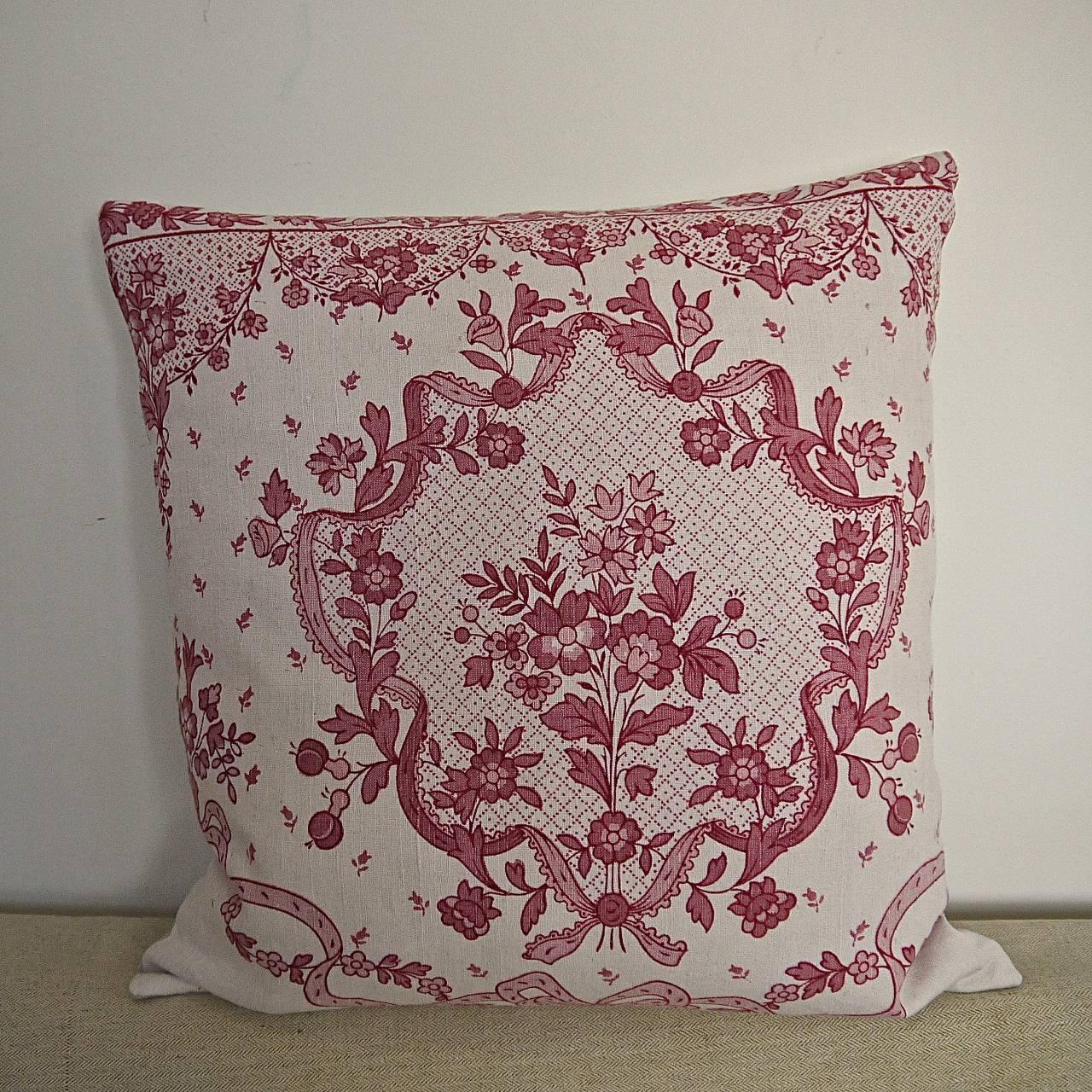Early 20th century French linen cushion printed with a pretty red and pink small bouquet of flowers surrounded by a frilled ribbon and bow.
Backed in a vintage French linen and slip-stitched closed with a duck feather insert.