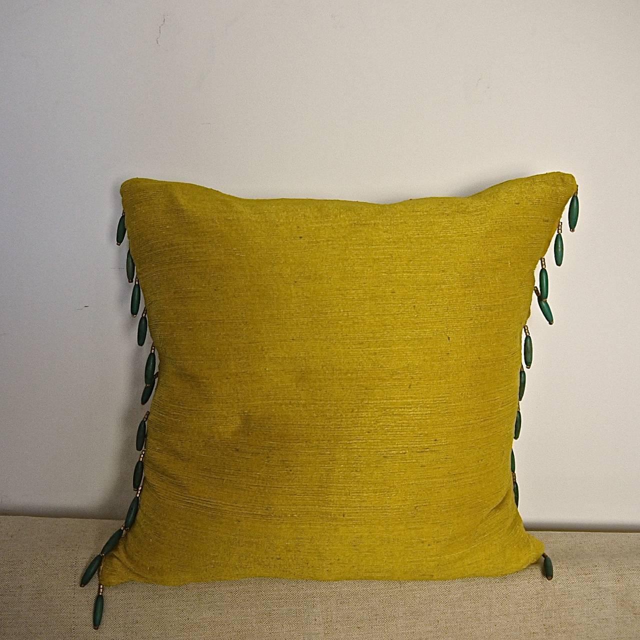Early 19th century French bourette de soie cushion in a rich saffron yellow with a 1920s French green and gold wooden beaded trim and backed in the same fabric.
