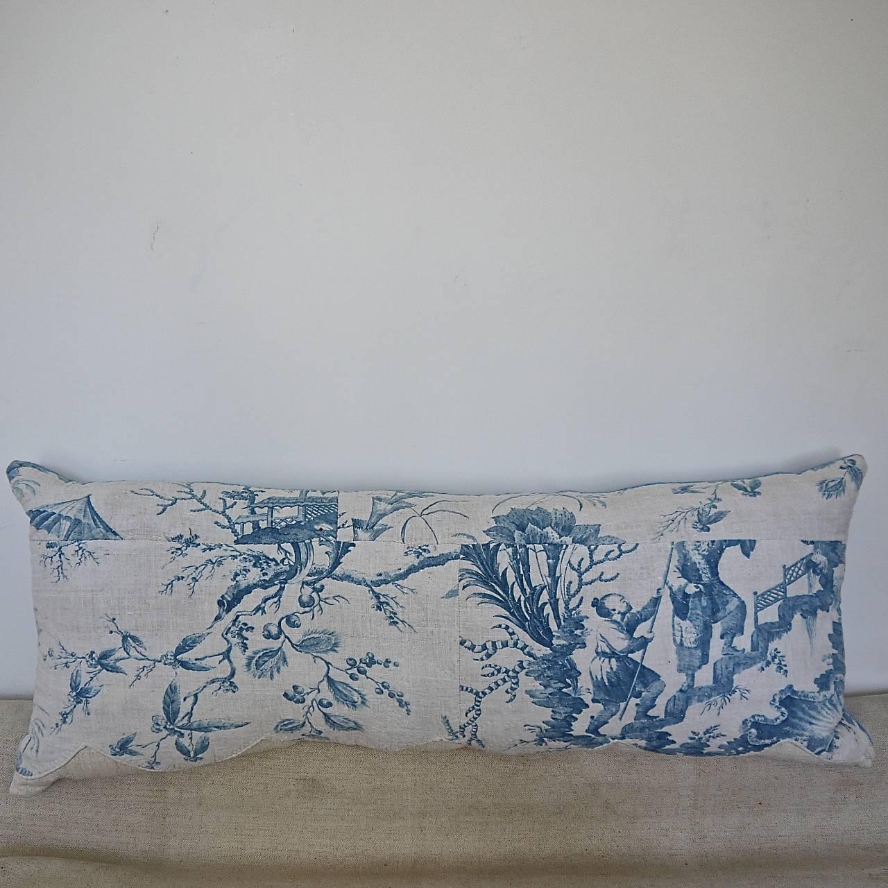  18th century French blue Chinoiserie cotton cushion made from a pelmet with its original patched pieces of large scale flowers,figures and meandering branches.It retains its original scalloped edge which has been stitched onto a 19th century French