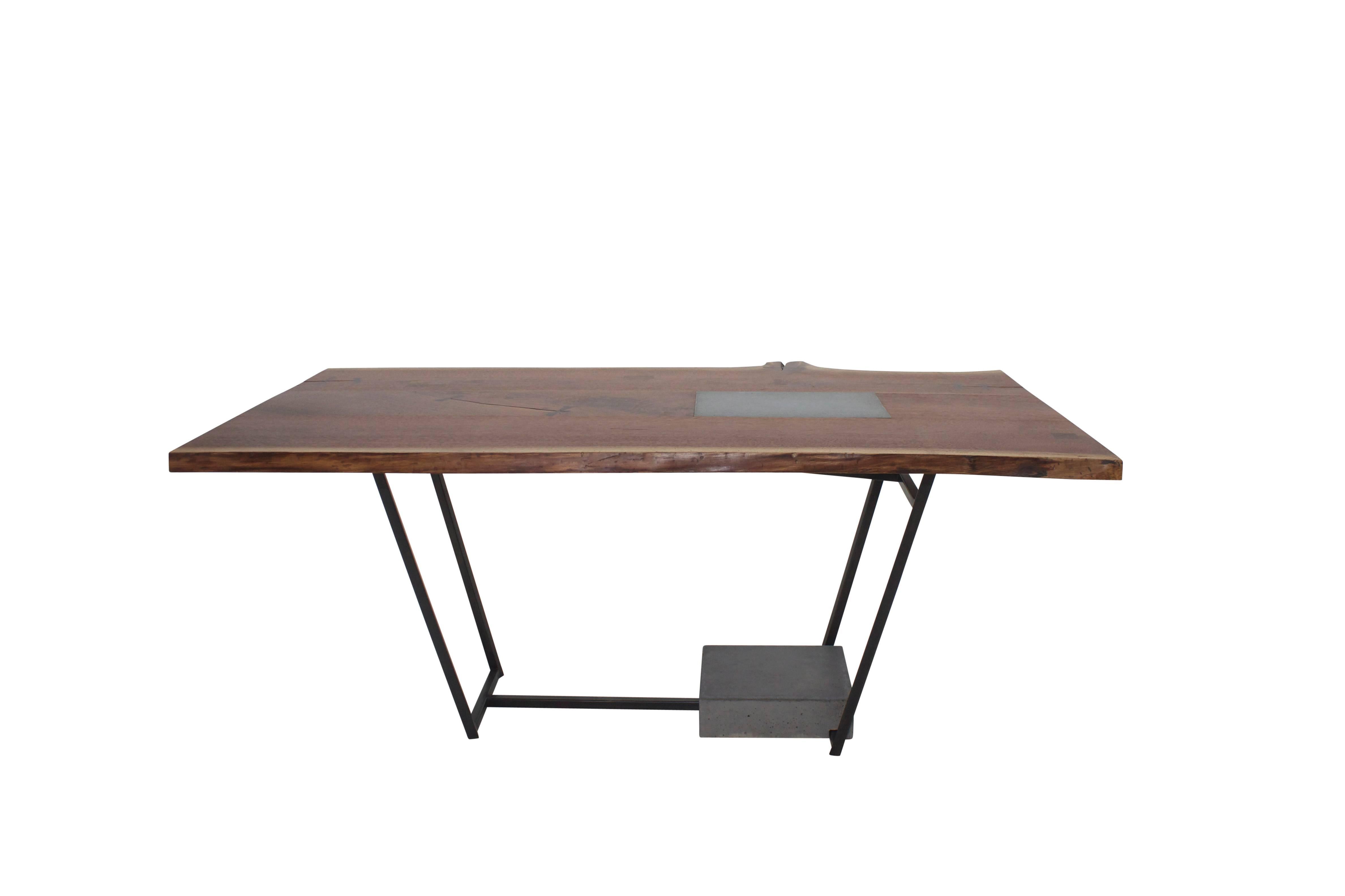 The SCW Table combines three elemental materials steel, concrete and wood. The top is constructed of live-edge walnut boards. Walnut inlays cover knots and Gabon Ebony butterfly keys preserve the natural beauty of the splits. A cement inset is ideal