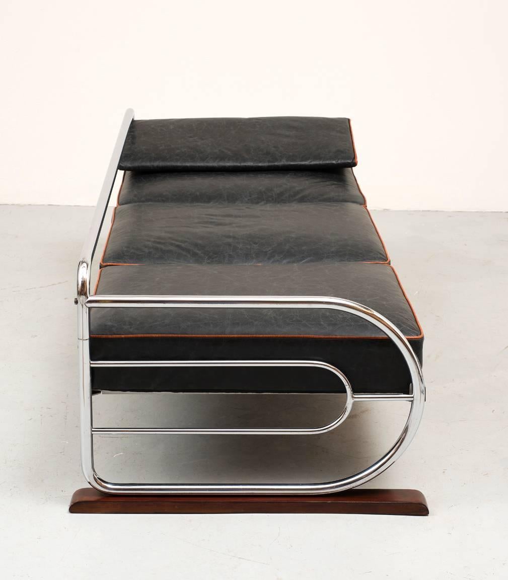 Bauhaus sofa / daybed designed by Hynek Gottwald in Prague in 1930. Classic Bauhaus form with chromed tubular steel frame, restored wood accents, and cushions reupholstered in black aniline leather with camel aniline piping.