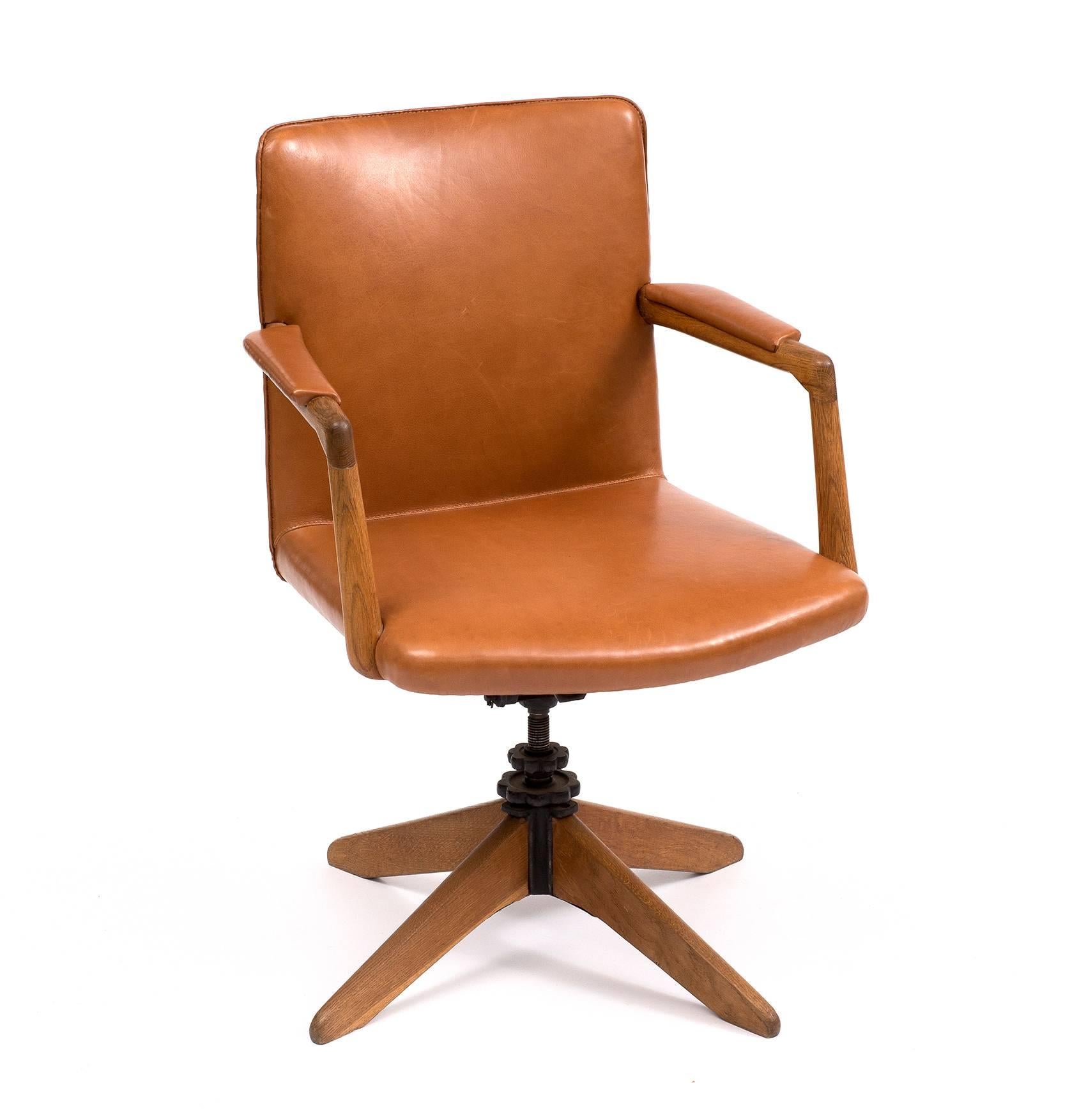 A rare and early design in oak with swivel and tilt function by Hans Wegner. Seat and back in carmel leather. Designed in 1940s. This example manufactured 1940s-1950s by Planmobel.
 