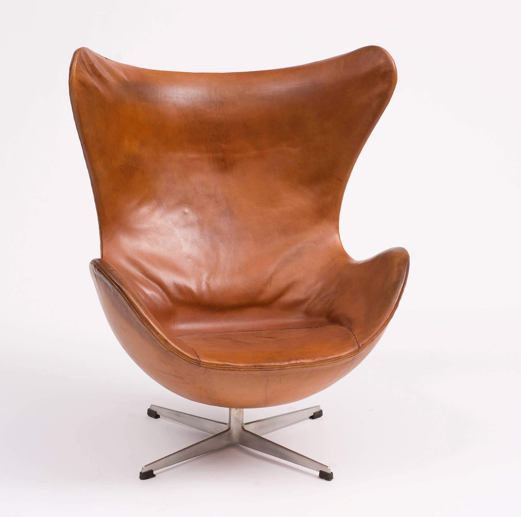 A first edition Egg chair by Arne Jacobsen in original cognac leather with lovely patina. Manufactured and stamped on underside leather by Fritz Hansen, Denmark, 1959.