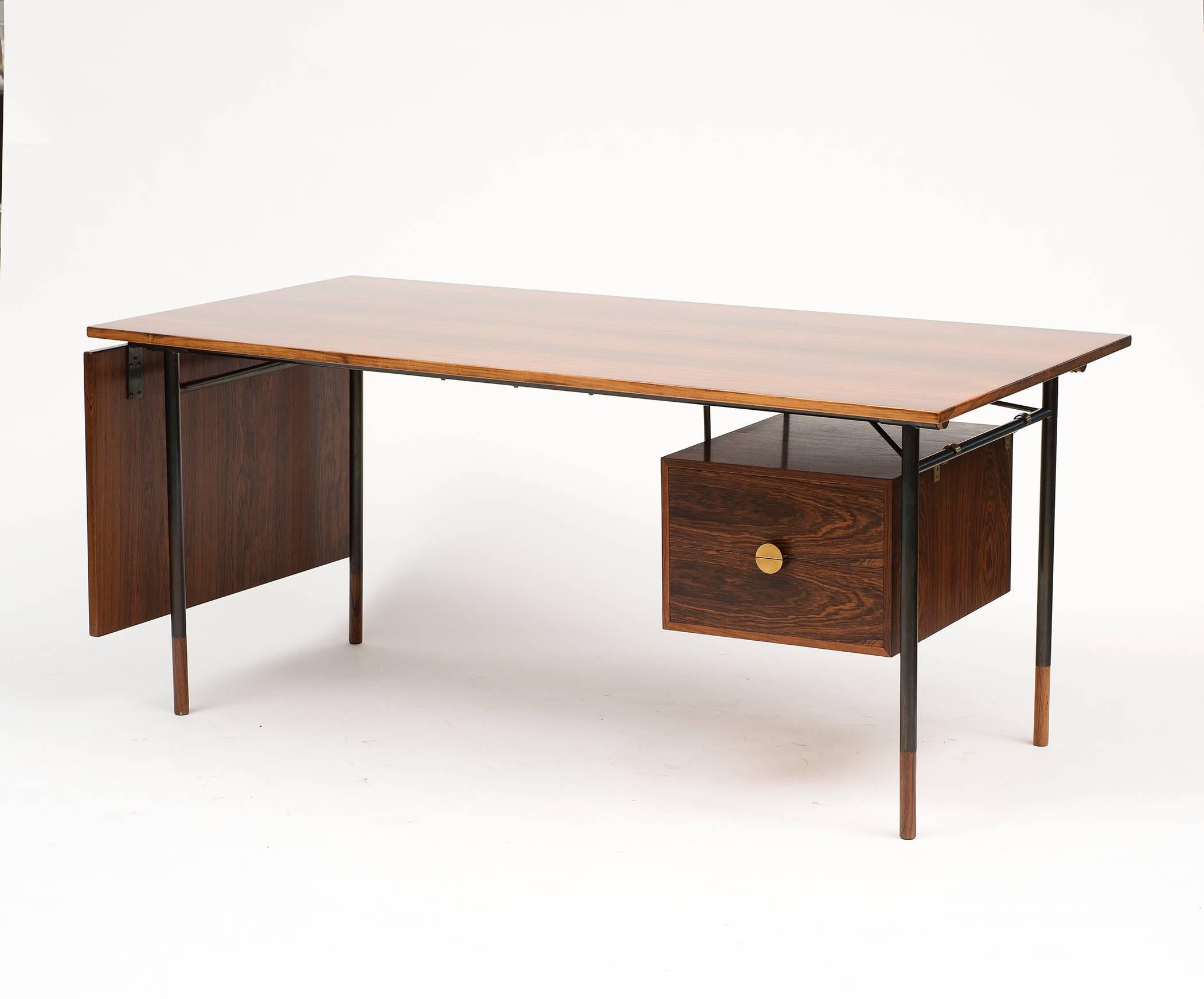 A rare rosewood desk, model BO 69, by Finn Juhl with drawer box in rosewood and demilune brass pulls. Tubular metal frame with gun barrel patina and tall rosewood shoes. Tray and drawer box are both removable.  A fine example of the elegant design