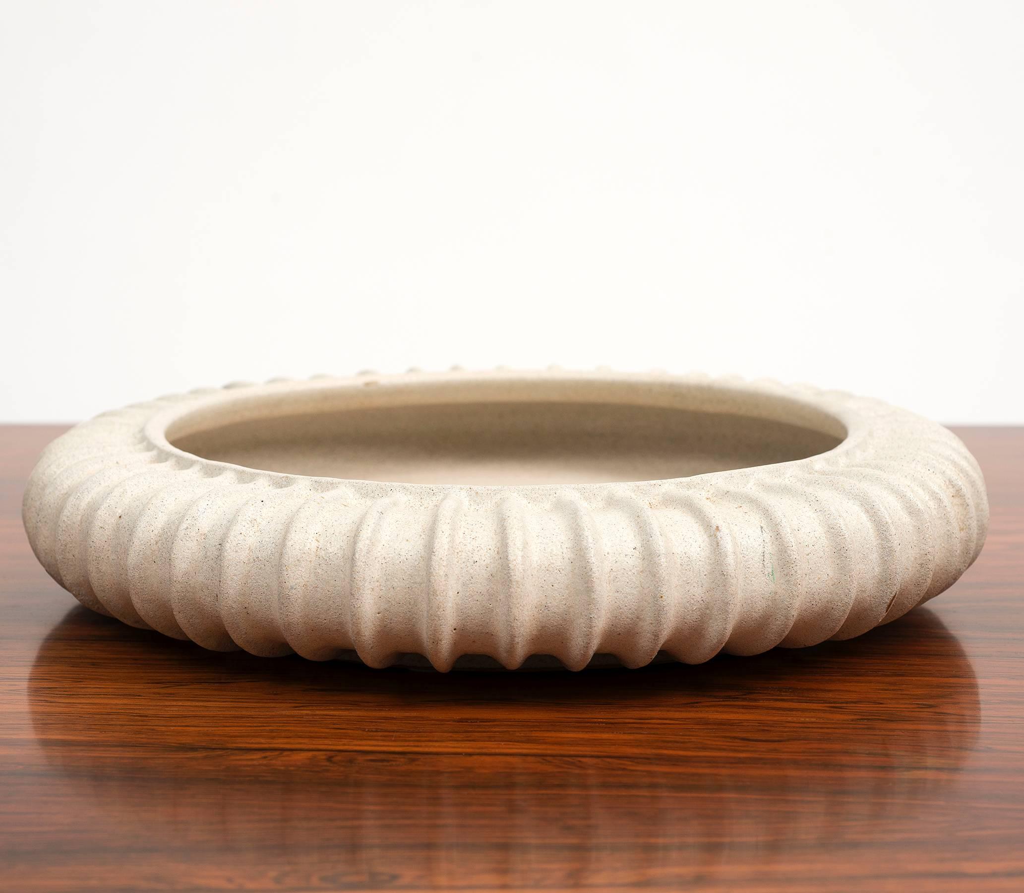 A large circular stoneware dish by Arne Bang with fluted exterior in a greyish white glaze, Denmark, 1940s.