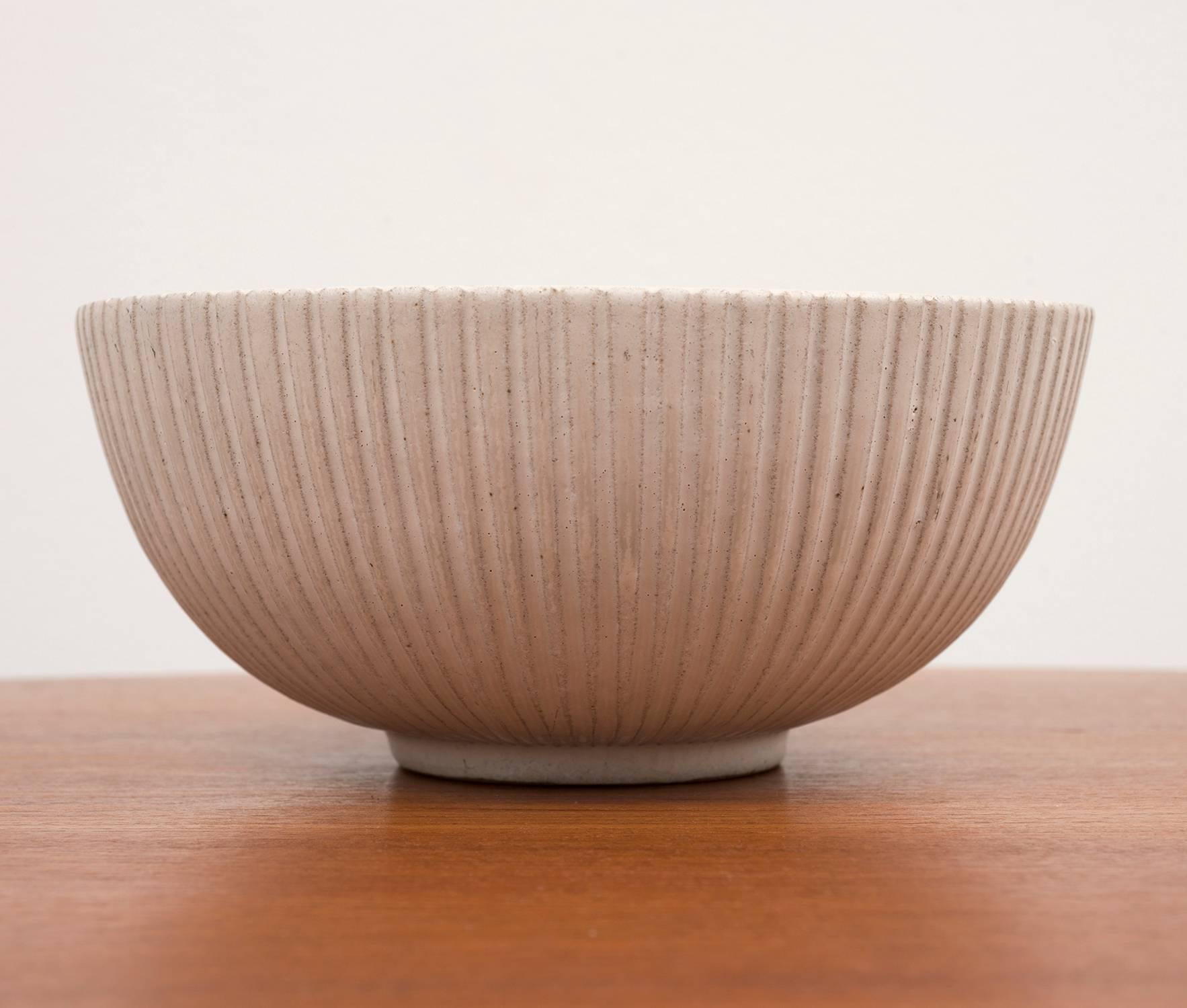 A stoneware bowl by Arne Bang with vertical fluted pattern on the exterior. In bisque glaze, Denmark, 1950. Signed 