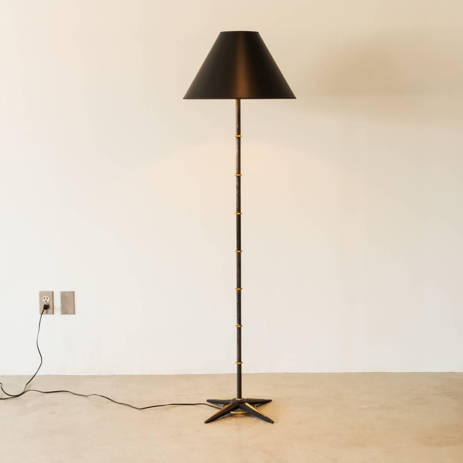 A Jacques Adnet floor lamp in iron and gilt metal with a star base. The black shade has a dramatic gold interior, France, 1950s.

Rewired for the U.S.