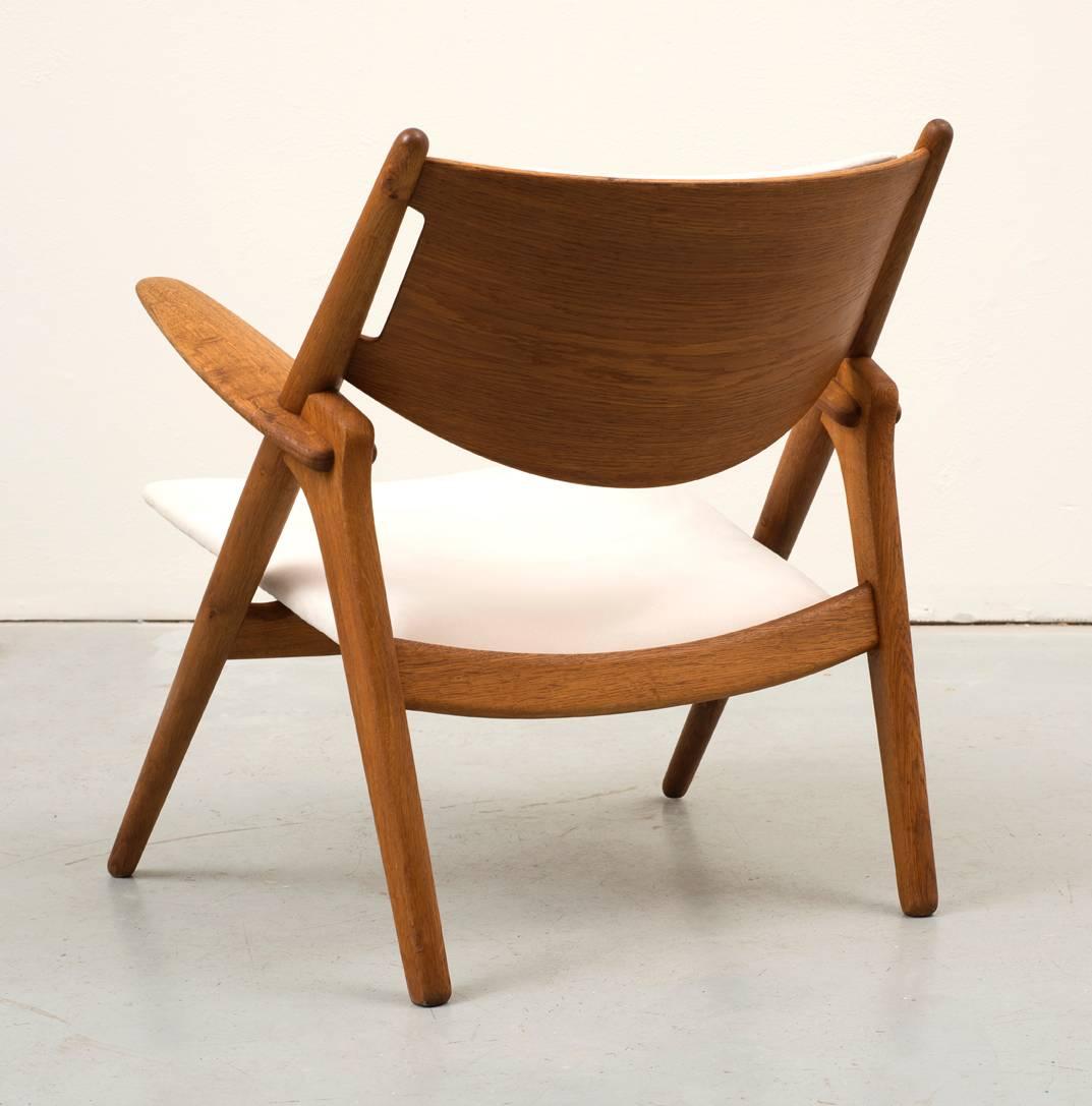 Original model CH28 Sawbuck chair by Hans Wegner. Designed in 1951 and produced by Carl Hansen and Son. This example in oak and white suede.