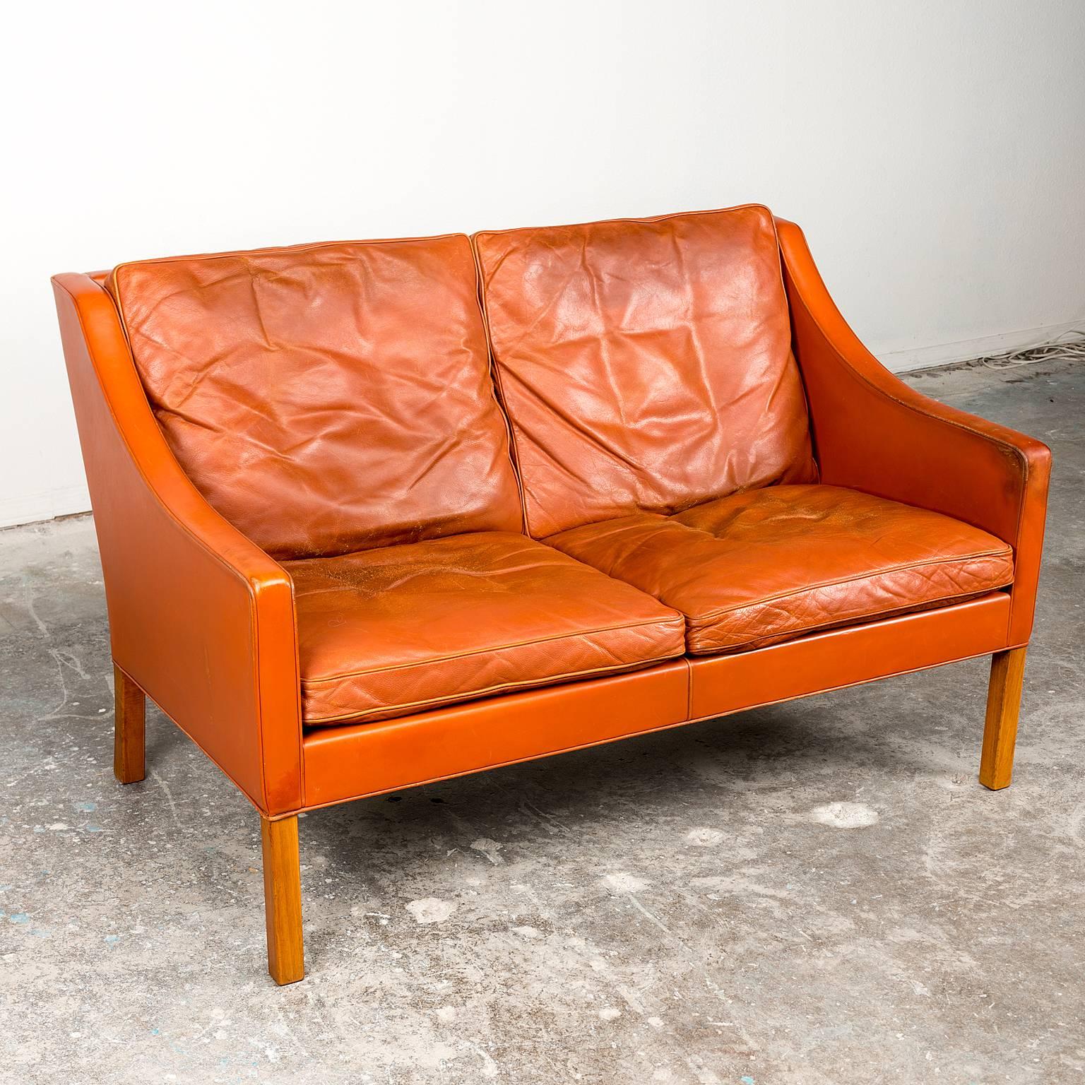A two-seat sofa by Borge Mogensen for Federicia Stolefabrik in well-patinated orange-cognac leather. Leather completely intact, beech legs in excellent vintage condition. Denmark, circa 1965.