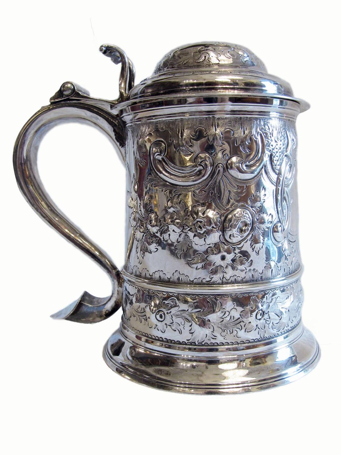 A decorative George III sterling silver lidded tankard with handle dating back to 1772-1773. Beautiful deep chased decoration to the body of flowers, foliage and scrolls. To the front there is a vacant cartouche. Gilt interior. As per images