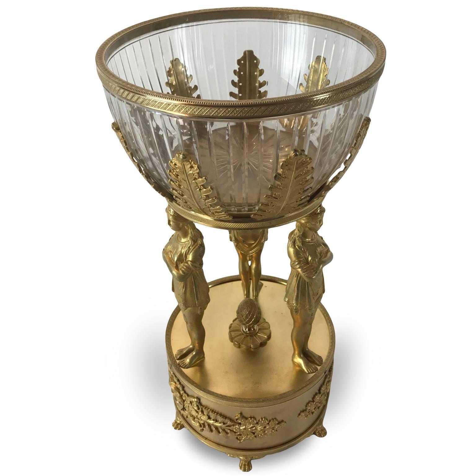 A magnificent early 19th century Empire gilt bronze figural centrepiece of French origin, dating back to circa 1820, with an original Baccarat crystal basket surrounded by palmettes, above three supporting caryatids, three standing female figures on