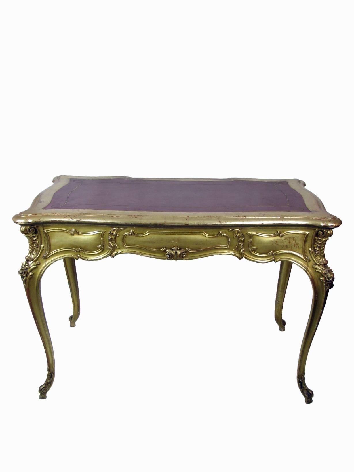 Mid-20th century carved and giltwood desk, Italian writing table, Louis XV style, in good condition, coming from a Milanese private residence. Red leather top and three drawers in the front, a wide, deep, central one, with a working lock and two