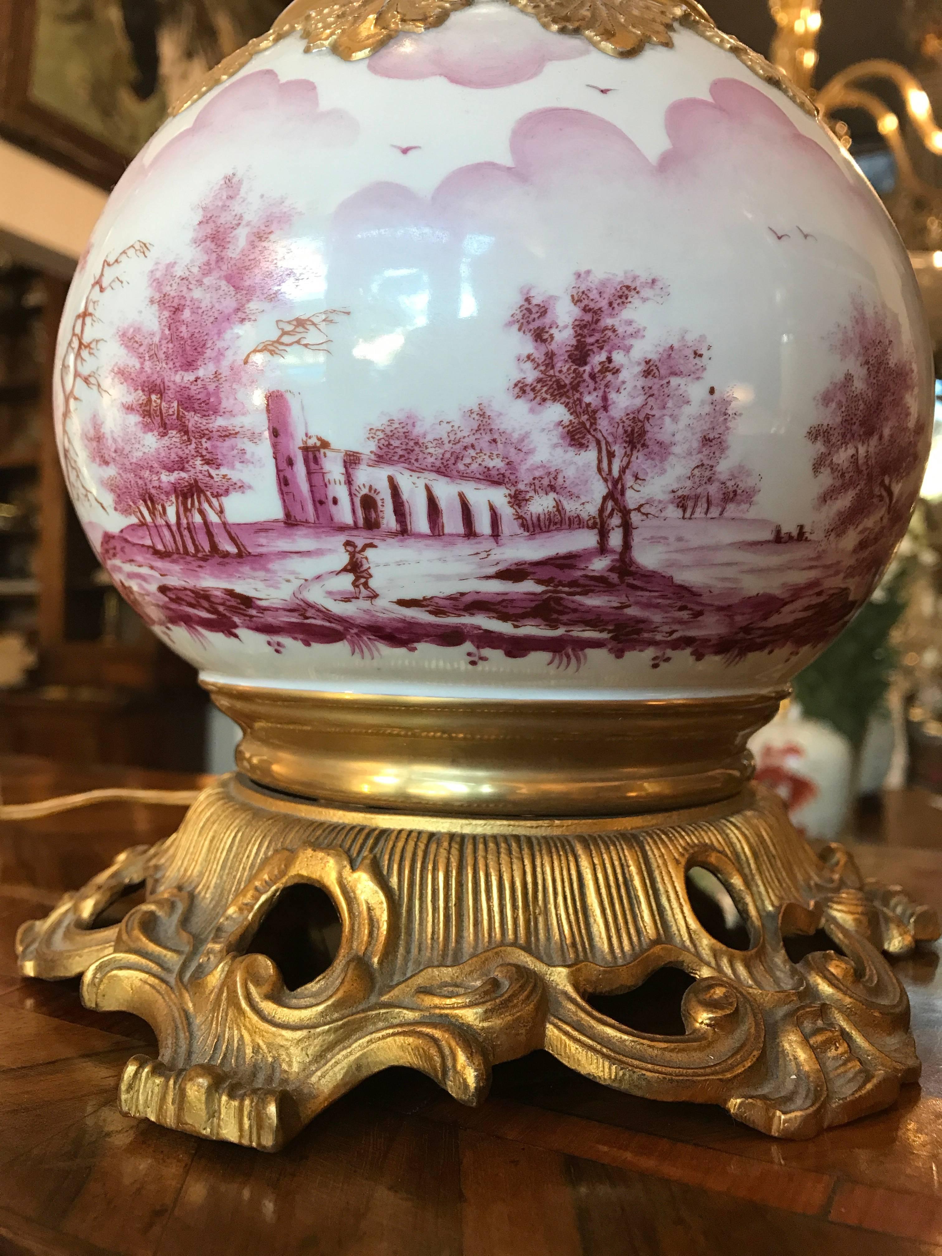 Mangani Firenze porcelain and ormolu table lamp, circa 1970, a circular table lamp with a gilt bronze basement, a porcelain vase with an all round rose decoration depicting rural landscapes with relief foliate gilded elements. Missing