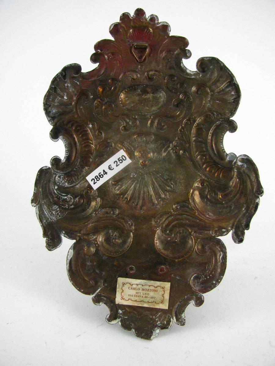 Antique shaped Holy Water font in Repoussé brass decorated with elegant scrolling curved curls, vegetal motifs and with a dove in the middle. In Christian religion dove is a symbol of peace and salvation. This embossed religious work is made in