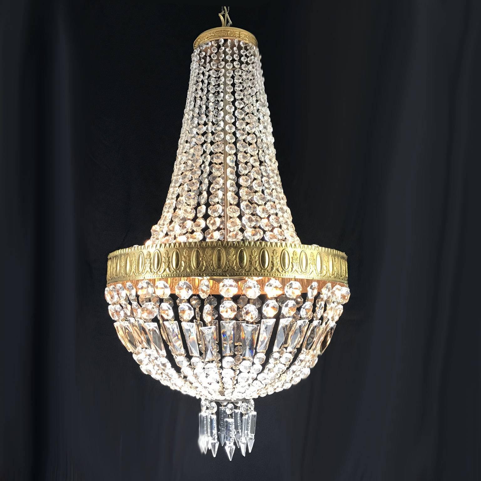 A 20th century Empire style chandelier with cast gilded bronze basket shaped structure, richly arranged with Bohemian cut-glass. Eight lights inside the larger bronze crown, rewired and fully restored it is now in perfect condition.

The cast bronze