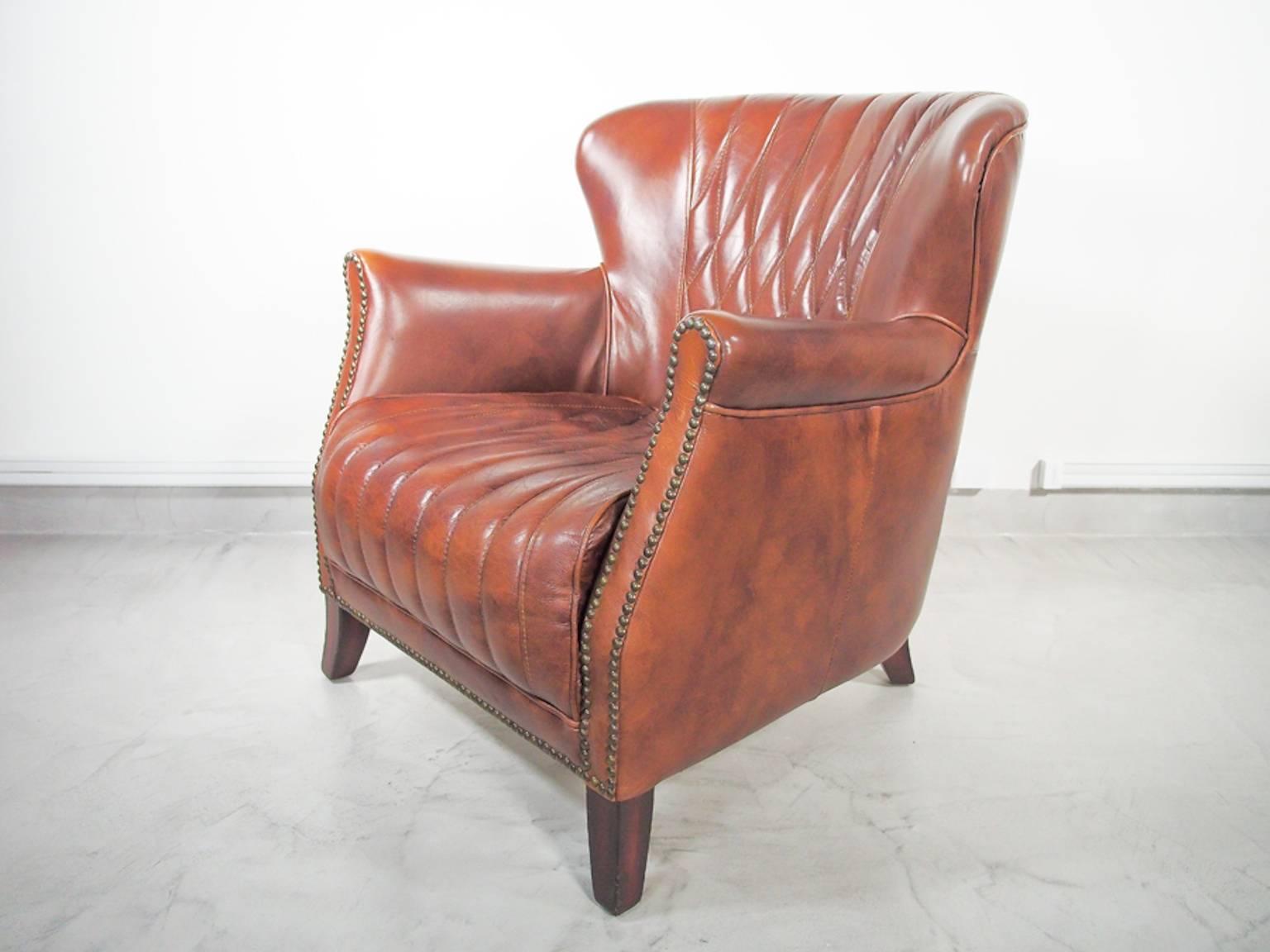 Stylish Chesterfield type tobacco leather armchair. Quilted back and seat, wooden legs and nail head details.