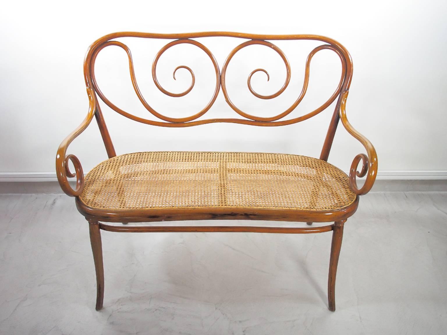 Rare bentwood sofa with rattan seat designed by August Thonet, the son of Michael Thonet, who in 1869 started to manage the family business. The settee from circa 1900 is in a good condition, but has a small hole in the rattan seat and a notch on